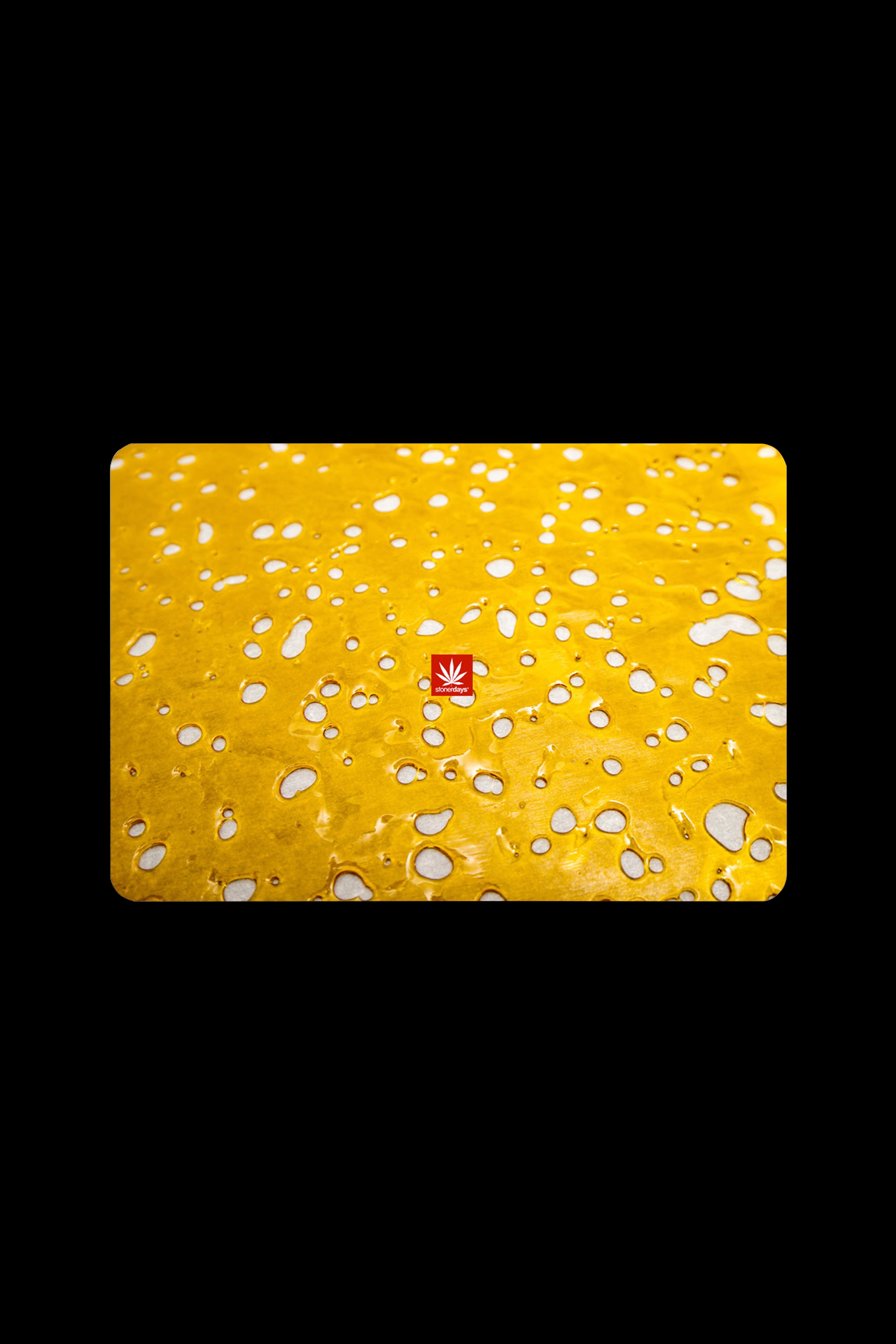 Close-up of a yellow silicone dab mat with cannabis leaf logo, covered in small oil droplets.
