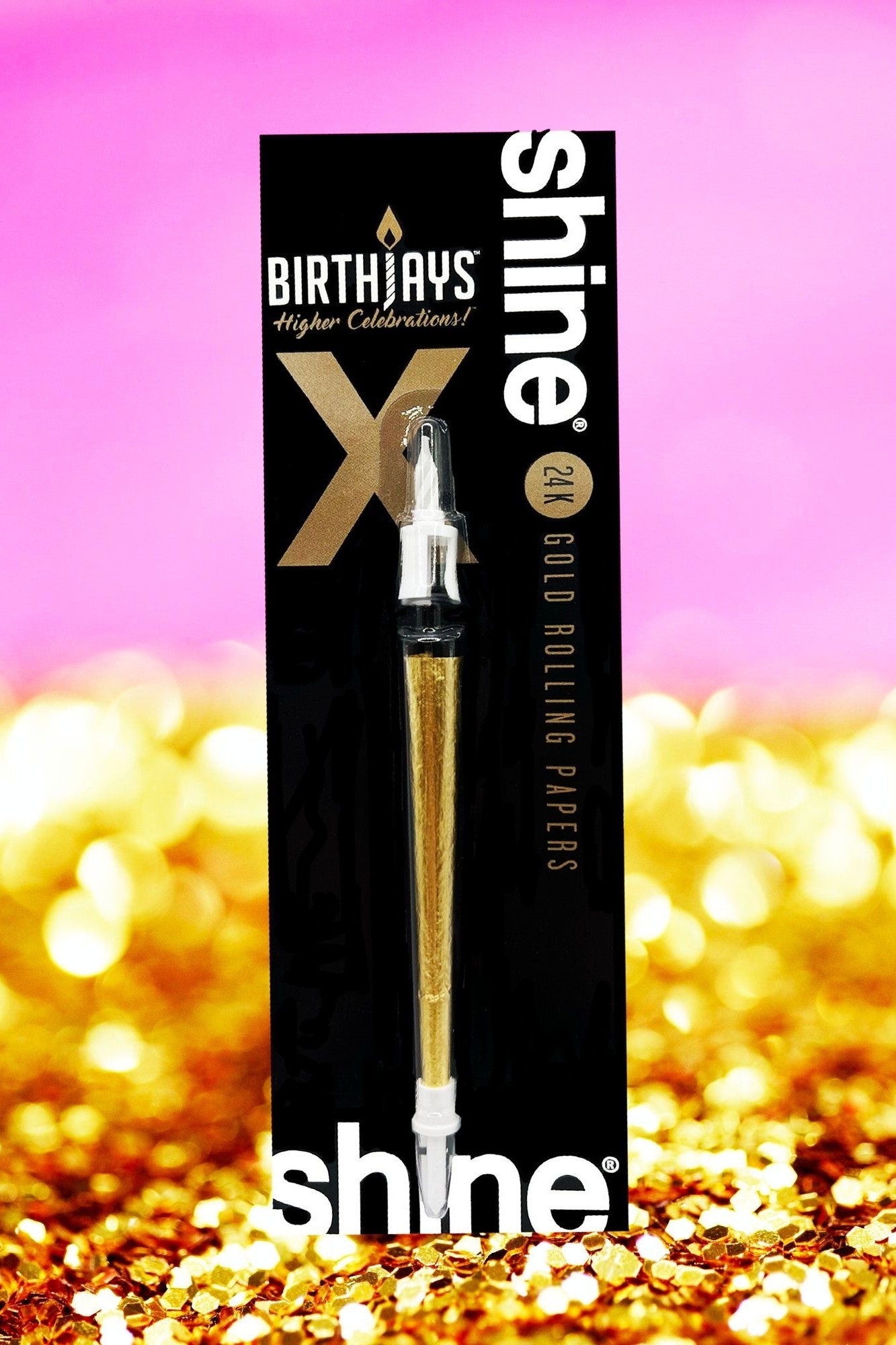 A black and gold package of Shine 24K gold rolling papers with a pre-rolled joint visible, set against a blurred golden confetti background.
