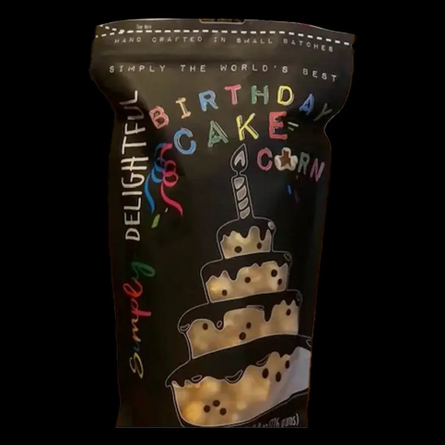 A black jar labeled โSimply Delightful Birthday Cake Cornโ with a hand-drawn illustration of a layered birthday cake with colorful sprinkles and a lit candle.