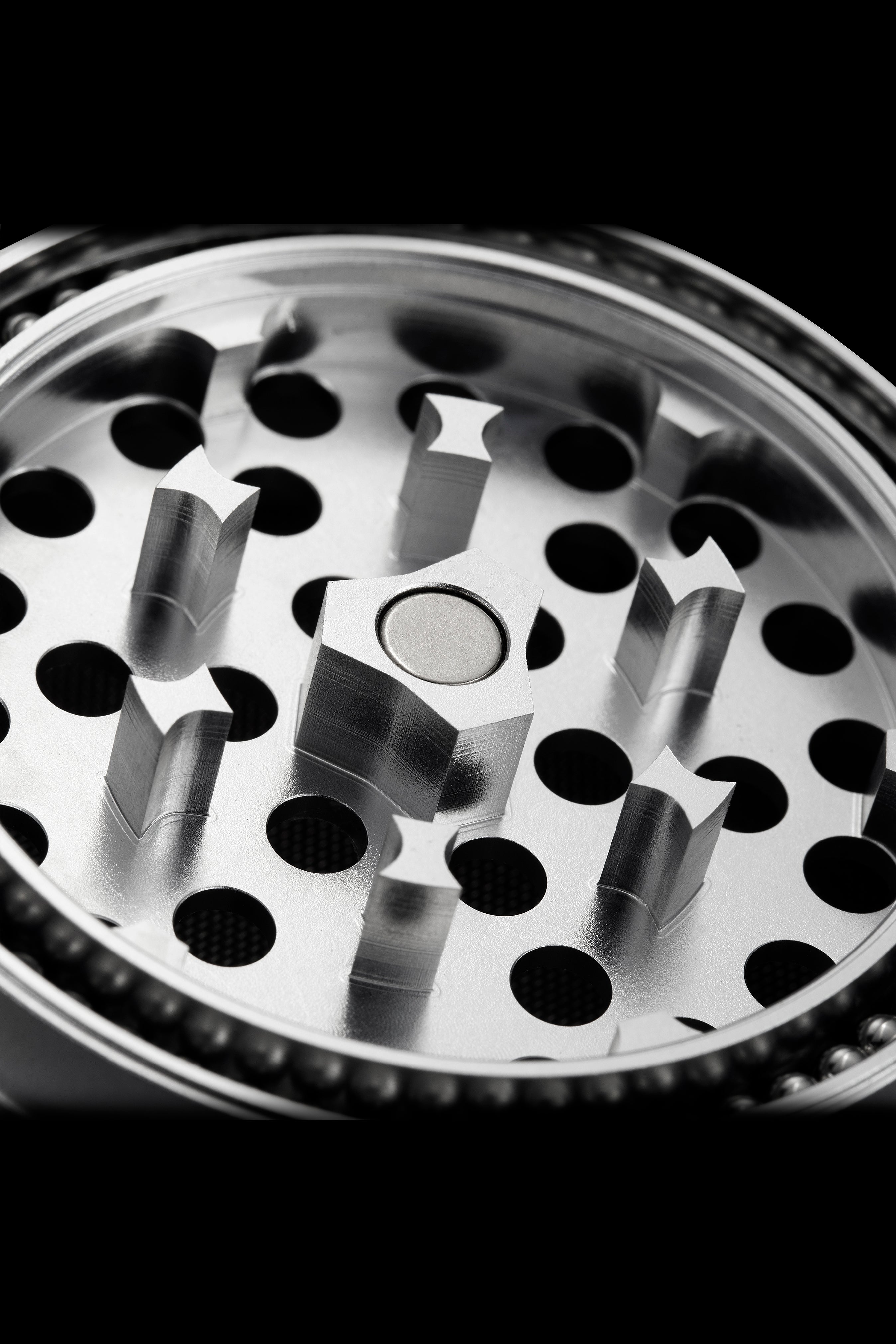 Close-up of a metal cannabis grinder with visible teeth and chambers.