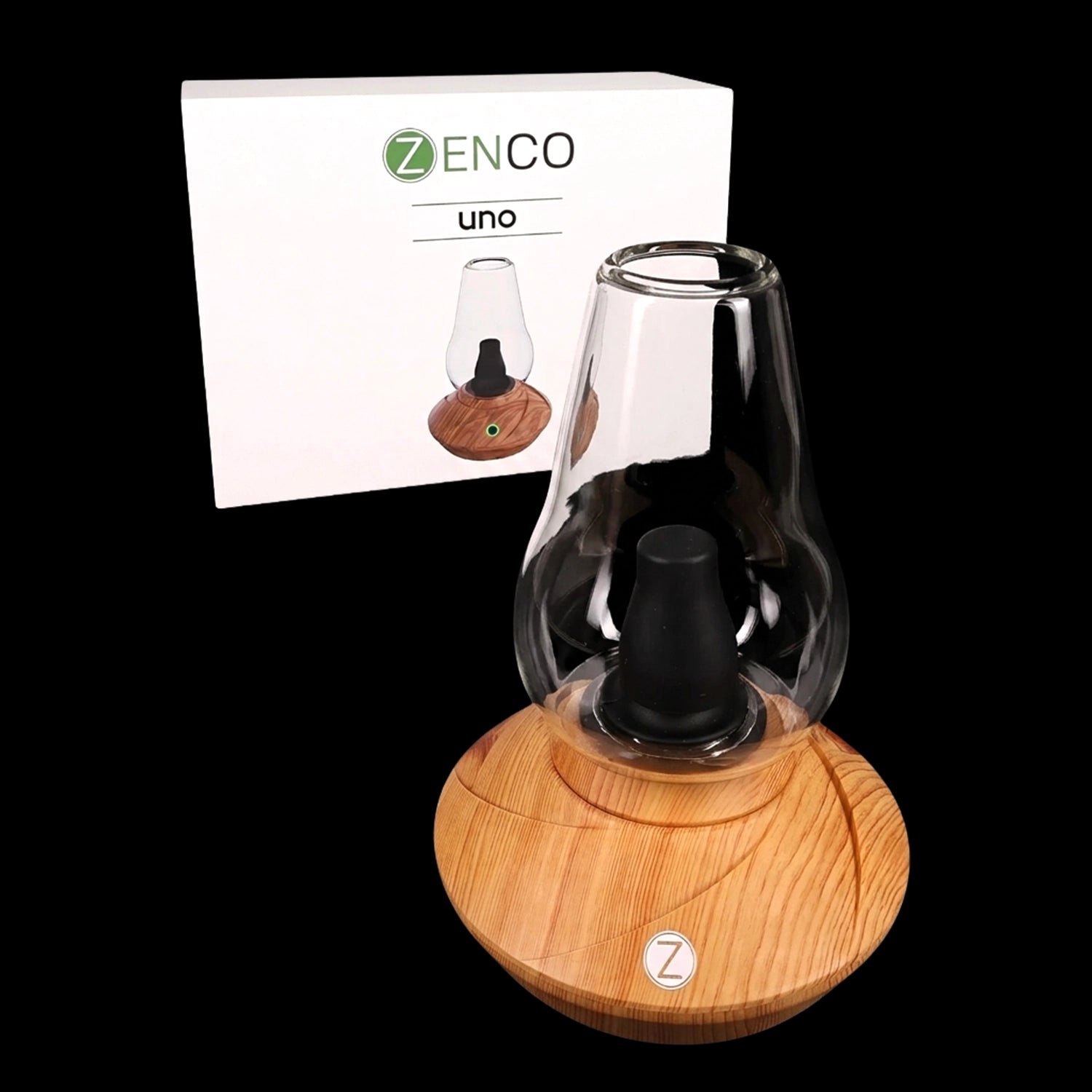 Angled close-up of the Zenco Uno Desktop Vaporizer showing its wood-textured base and clear glass top with product box in the background