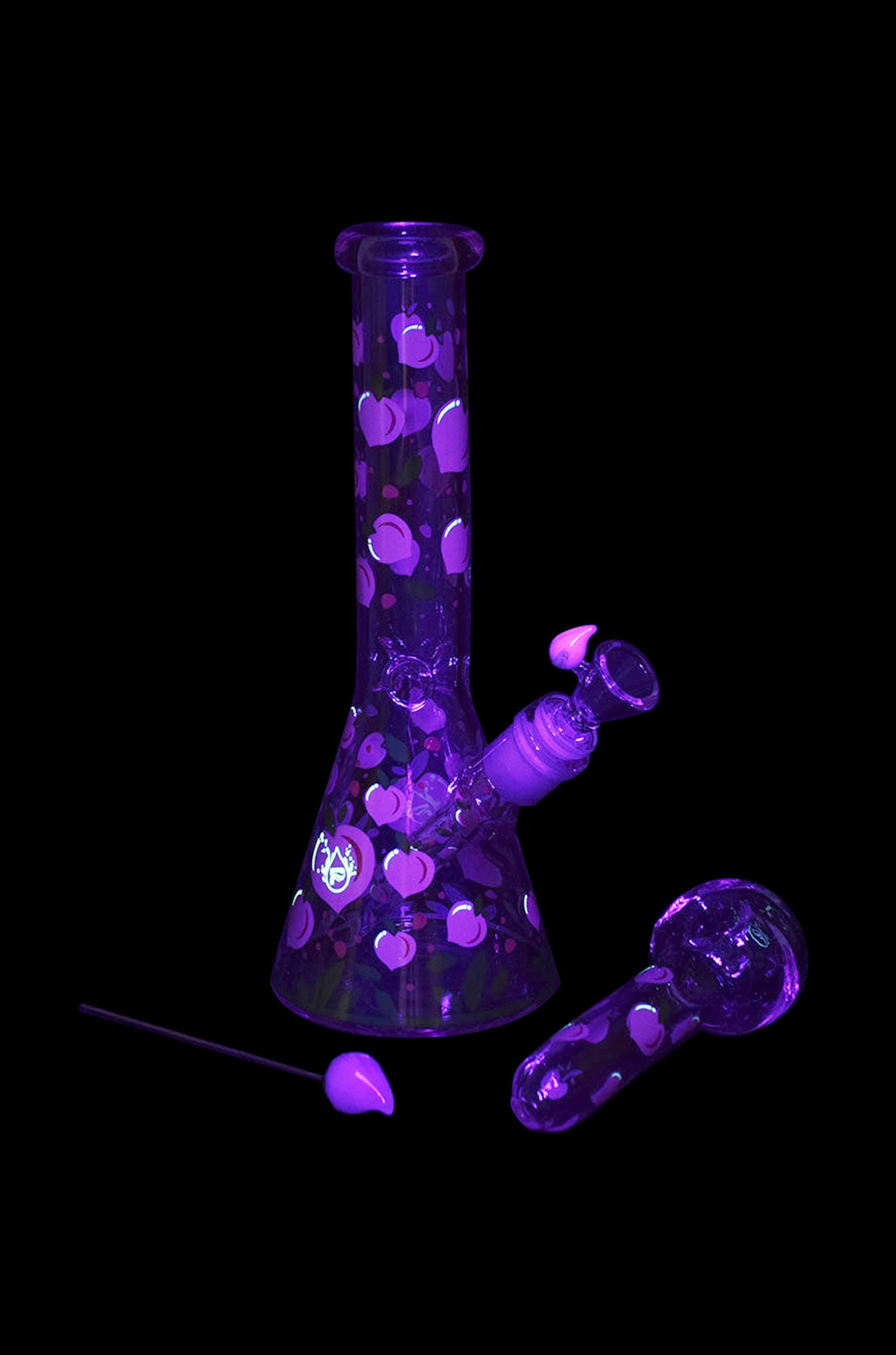 Glowing purple glass bong and pipe on black background.