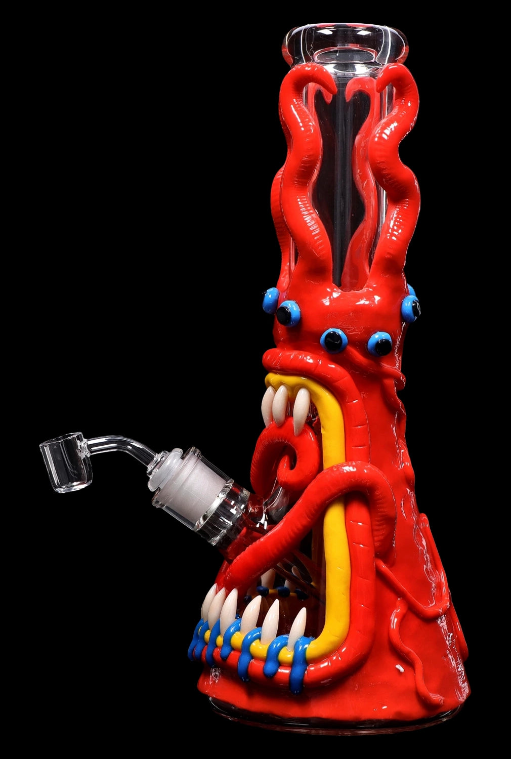 Red glass bong shaped like a cartoon monster with blue eyes, sharp teeth, and tentacle-like appendages, accompanied by a quartz nail.