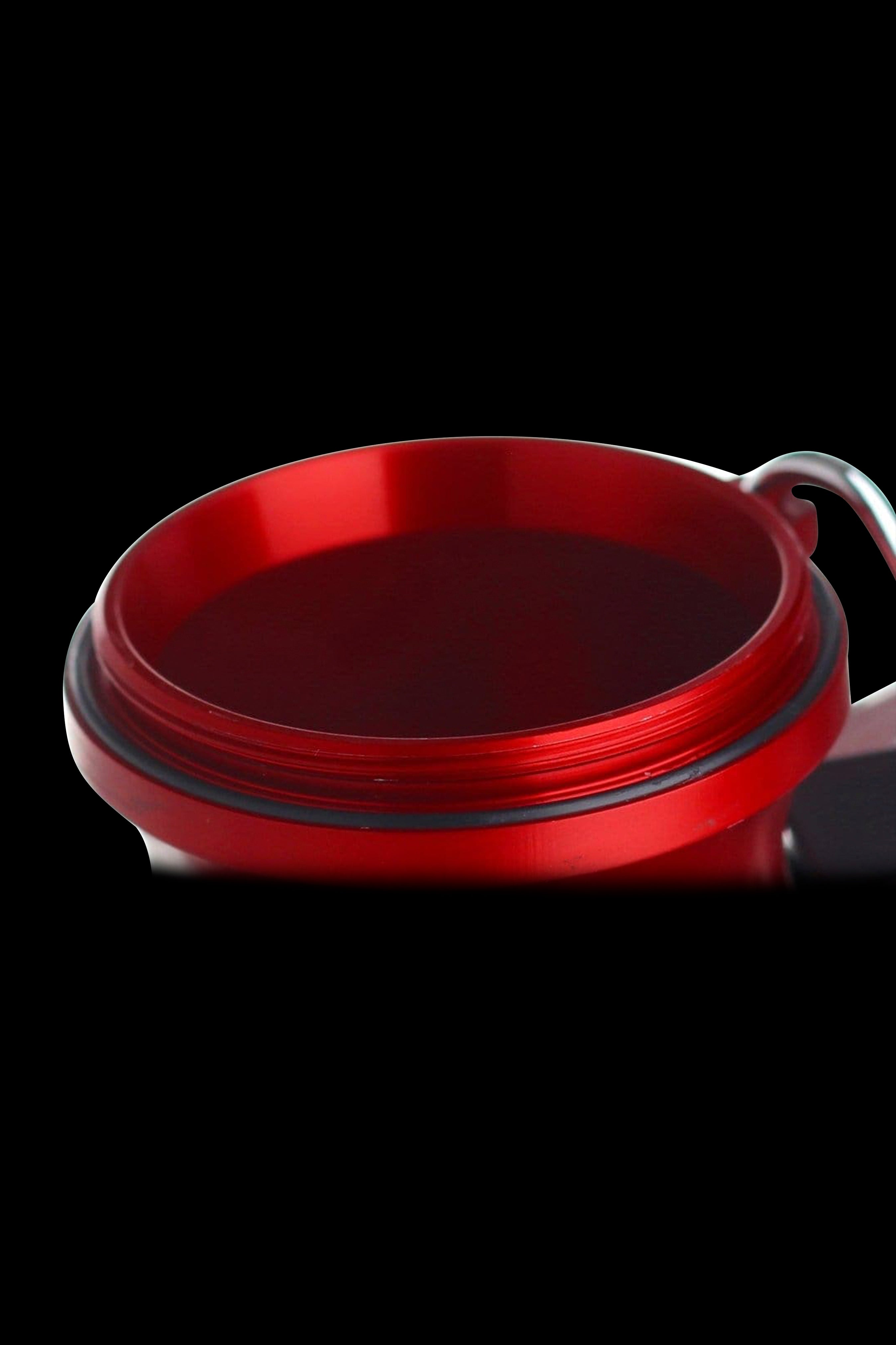 Close-up of a red, metallic cannabis grinder against a black background.