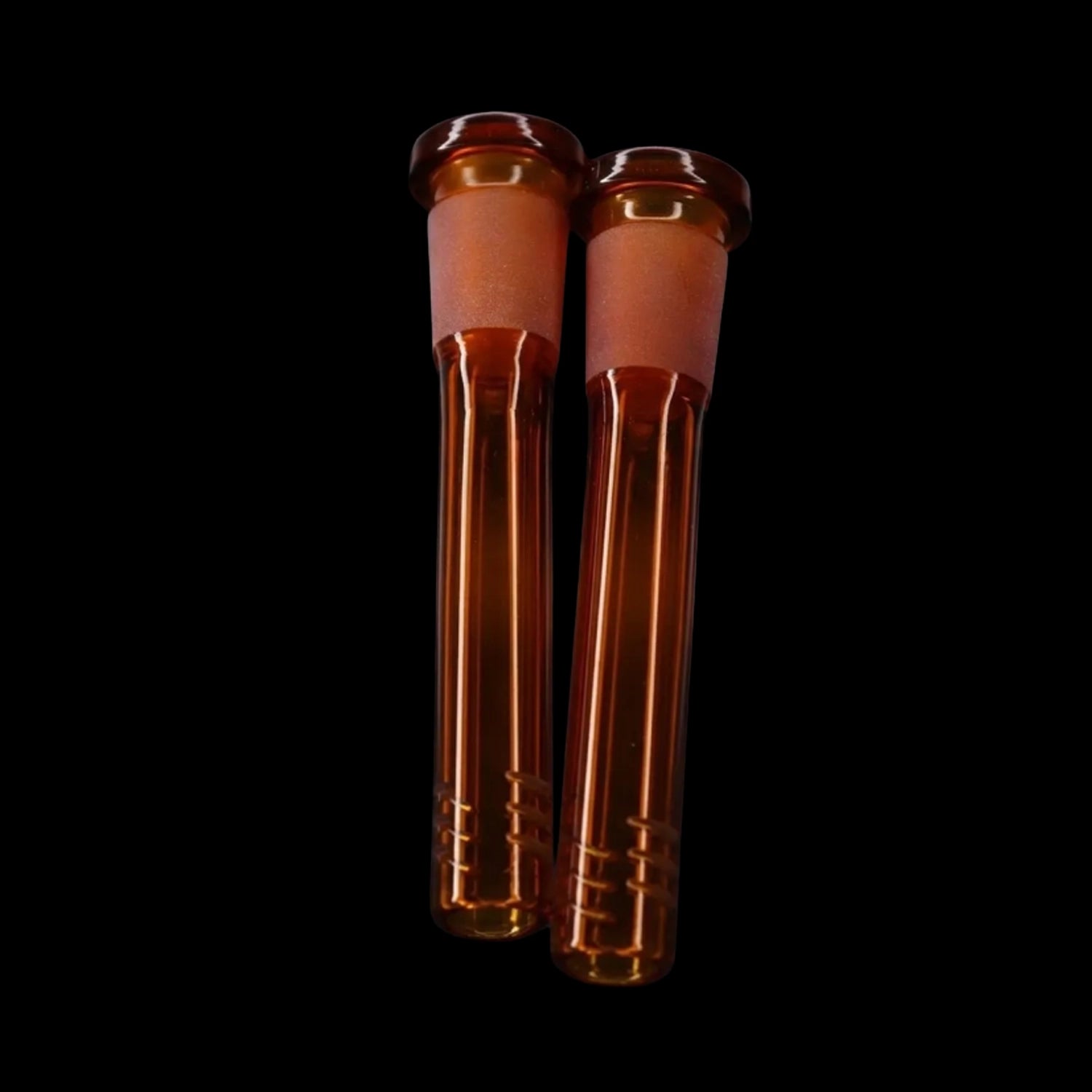 Close-up front view of two amber Smoke Cartel Color Diffused Downstem - 3 in. pieces against a solid black background.