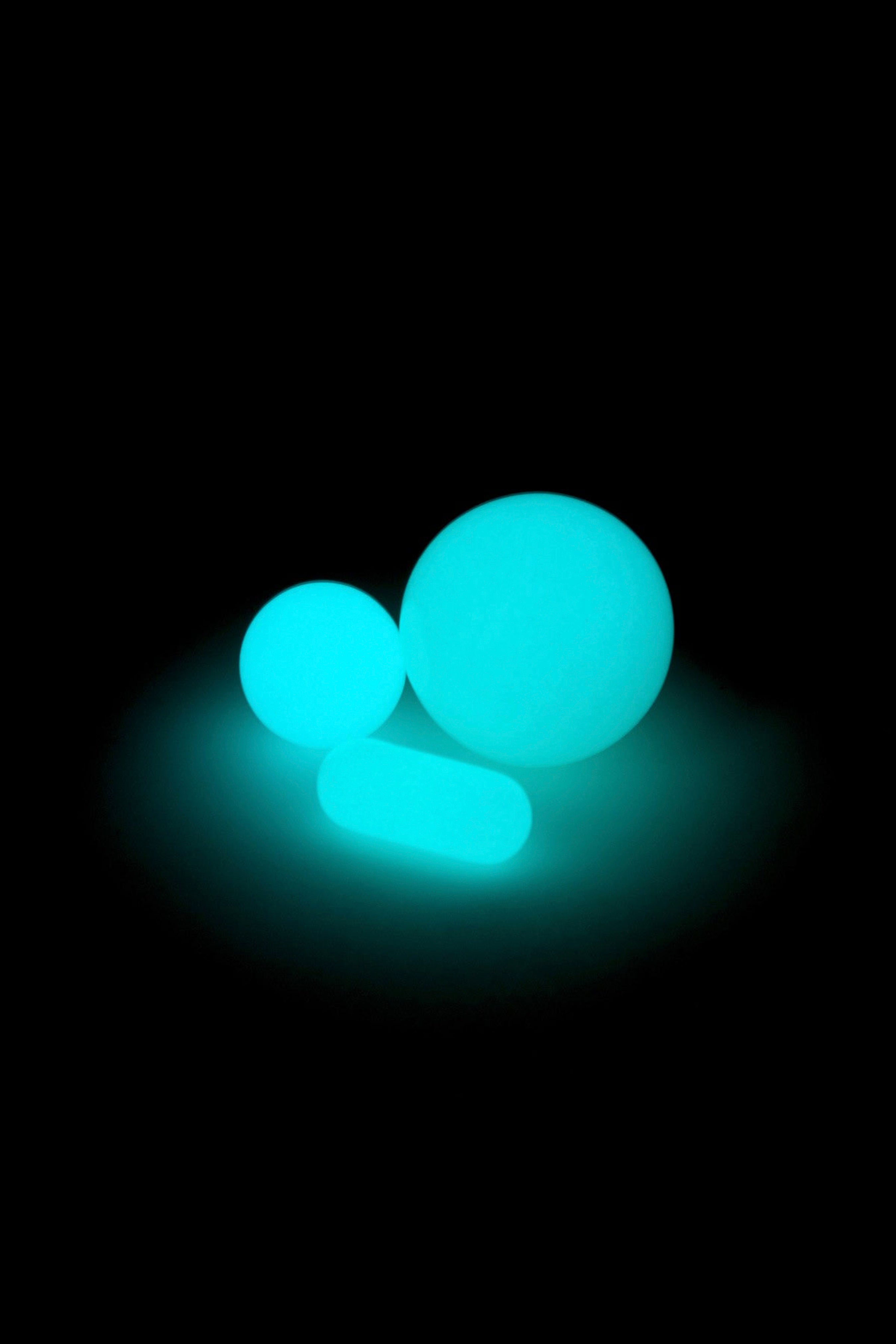 Glowing blue cannabis capsules on a black background.
