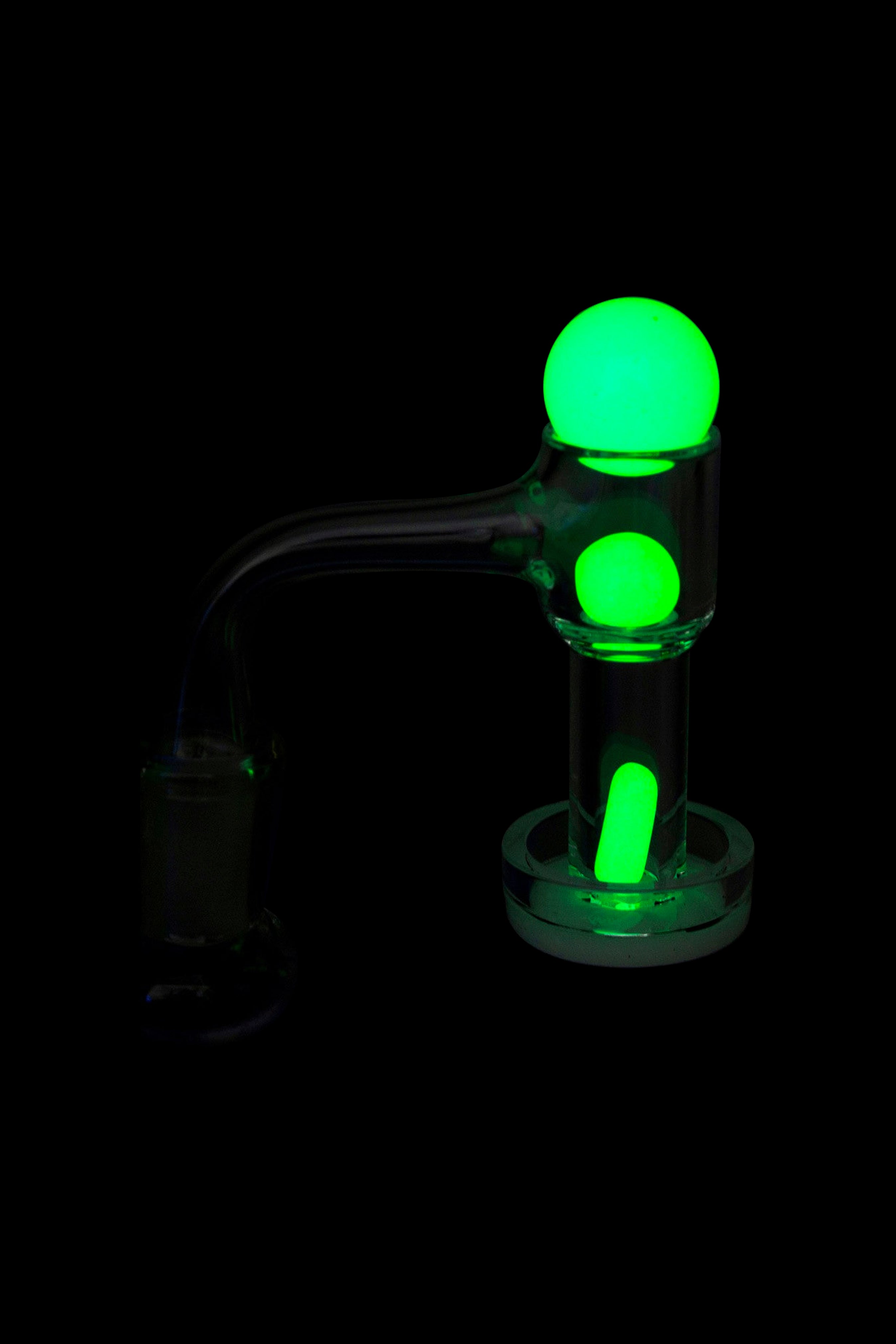 Glowing green glass dab rig isolated on black.