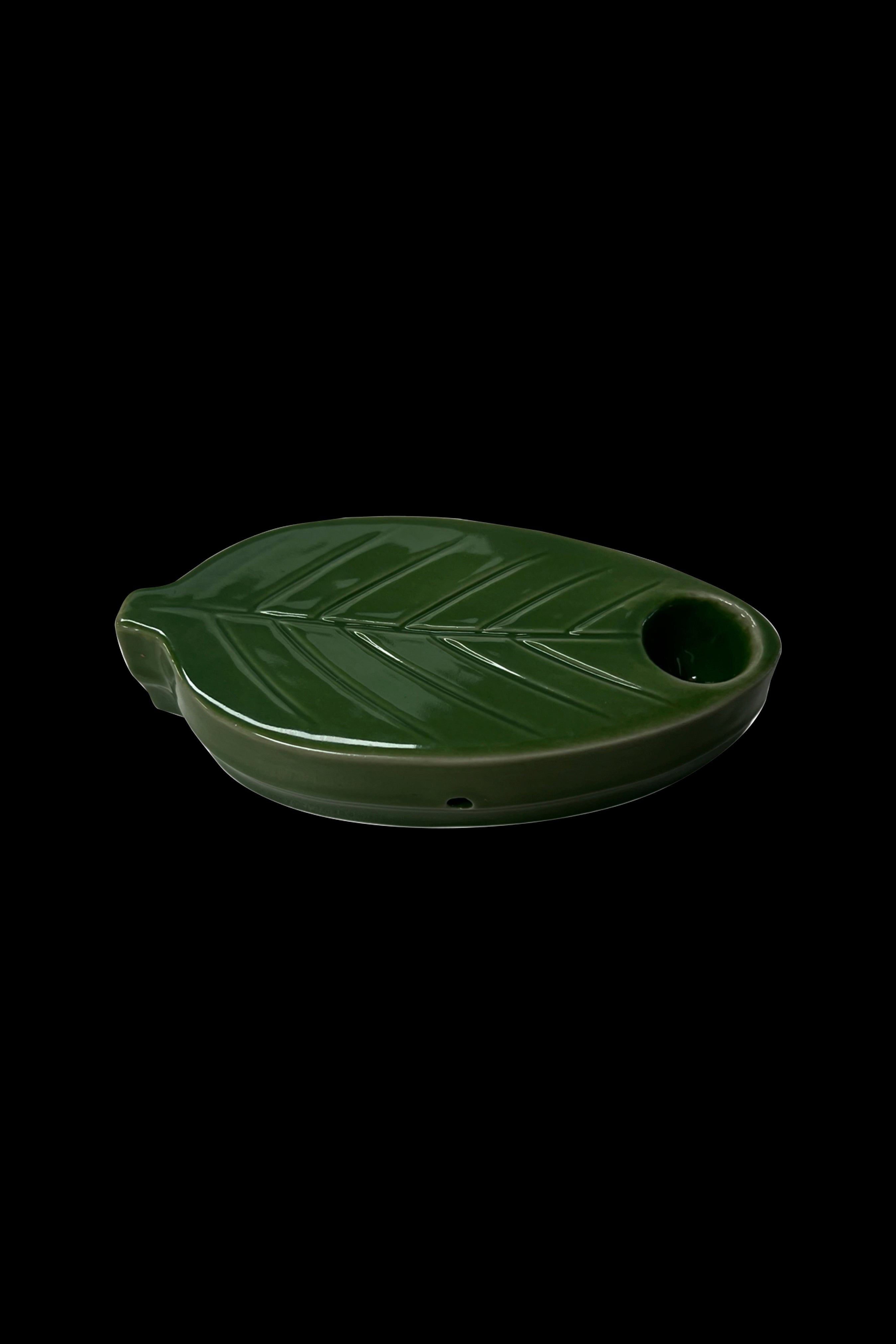 Green ceramic ashtray shaped like a cannabis leaf with a bowl-shaped indentation.