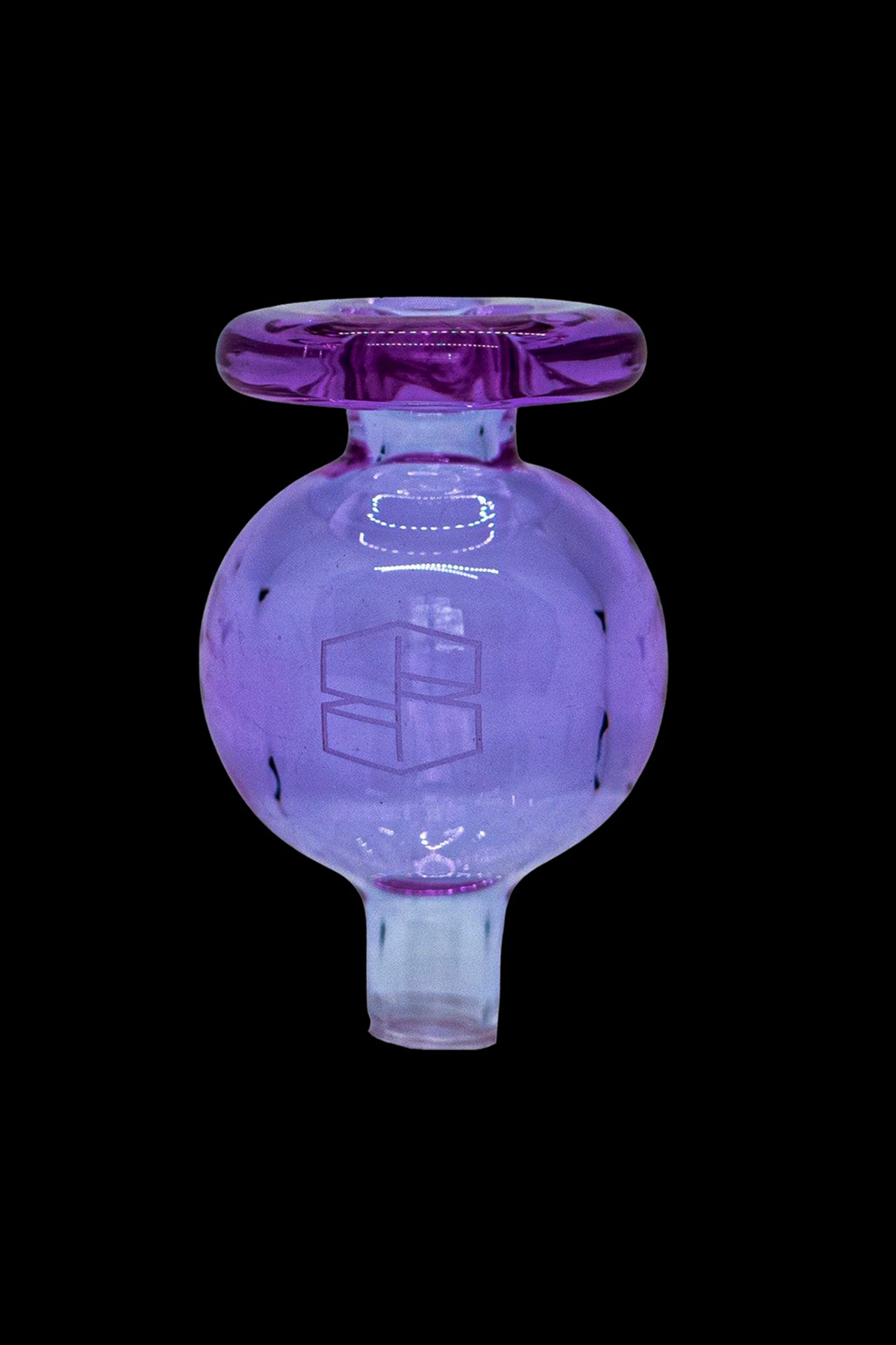 Purple glass dab rig carb cap isolated on a black background.