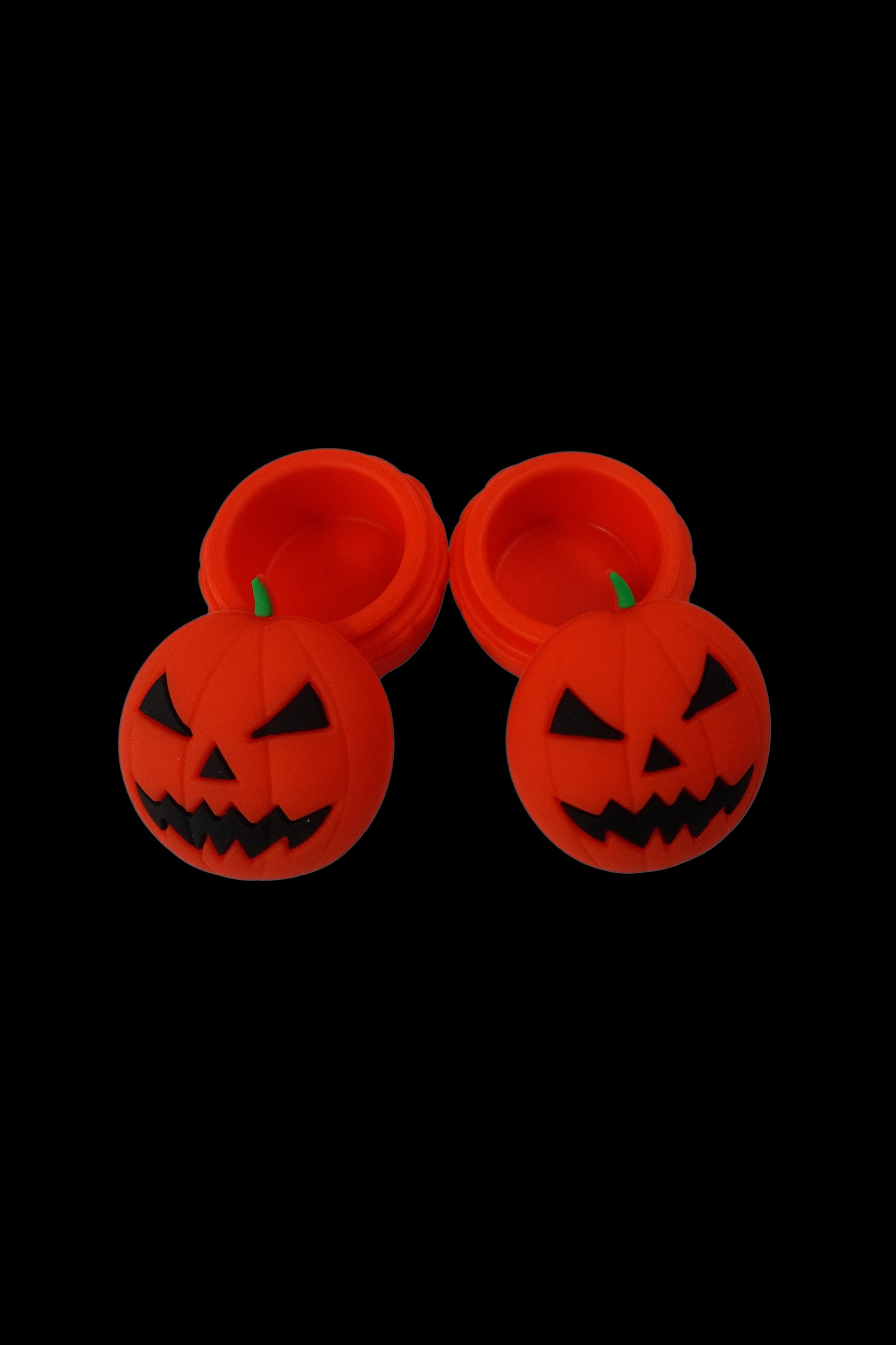 Two orange jack-o'-lantern shaped silicone concentrate containers against a black background.