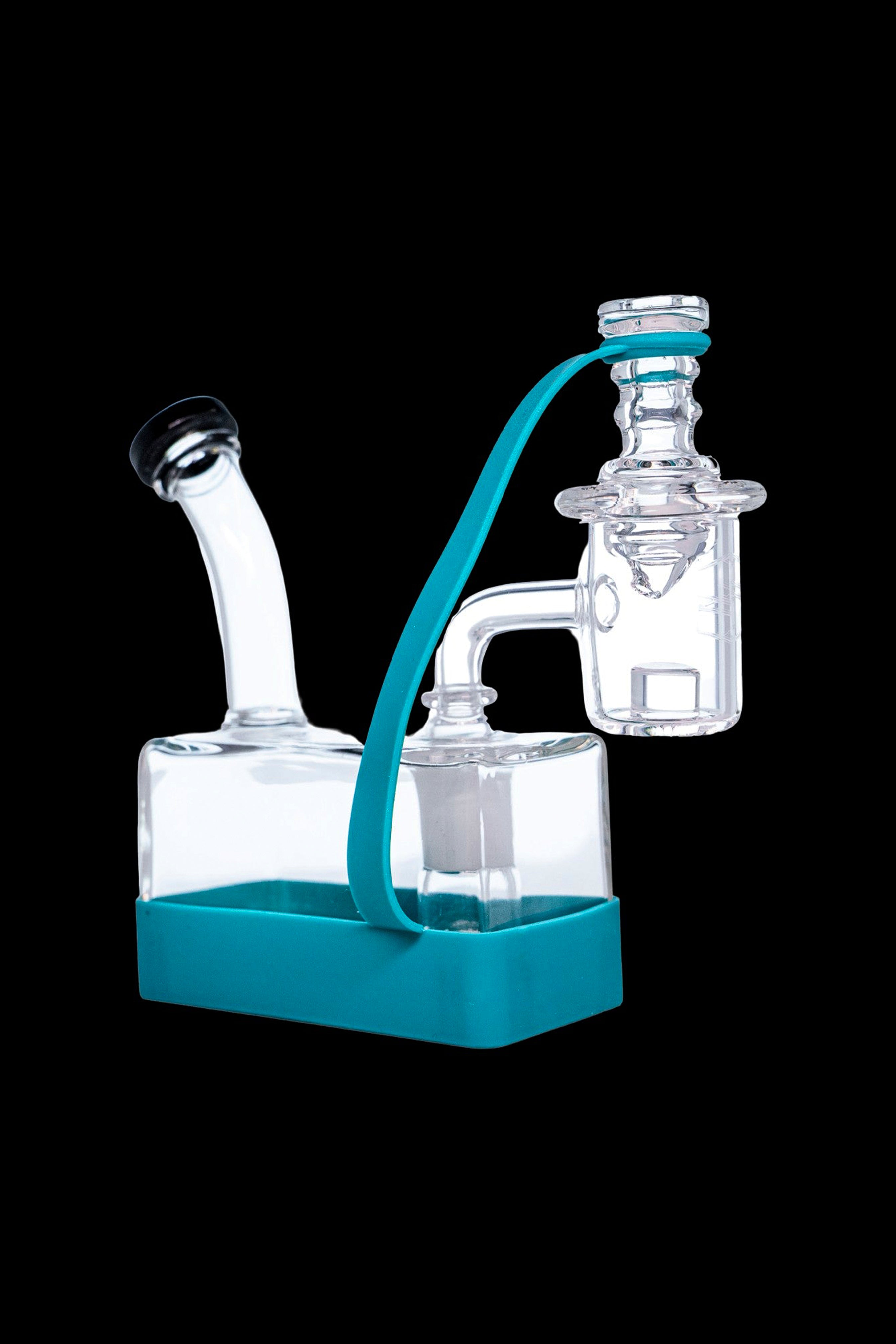 Clear glass rig with turquoise accents and a water chamber, isolated on a black background.