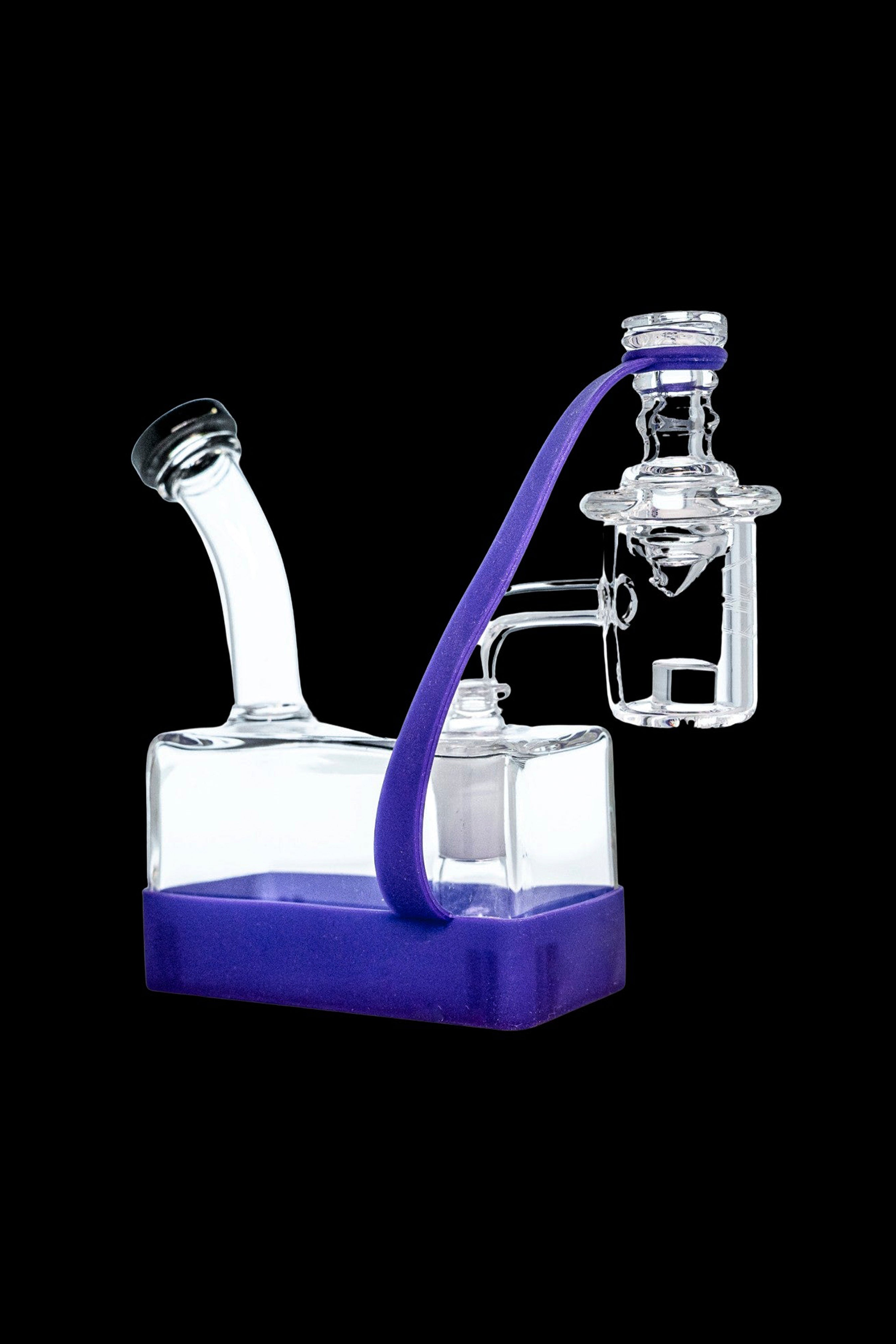 Clear glass water pipe (rig) with purple accents on a purple base, featuring a bubbler and mouthpiece, isolated on a black background.