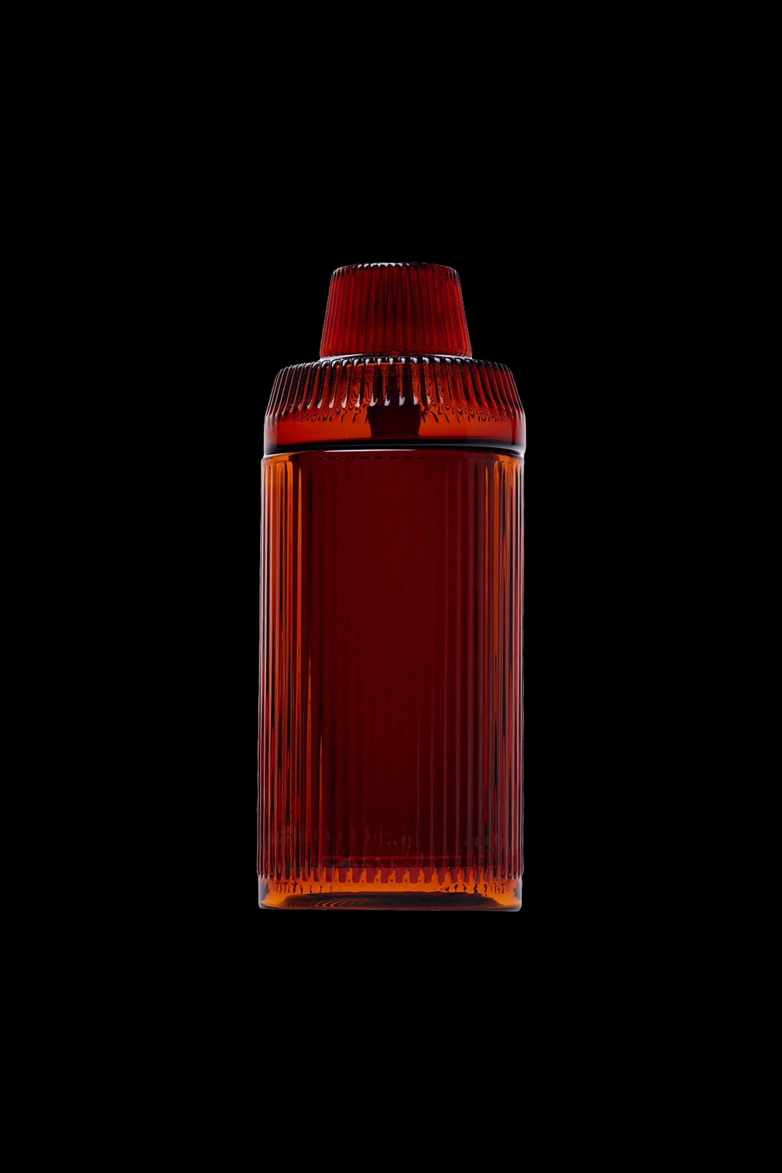 Amber glass cannabis storage jar with ribbed texture, isolated on a black background.