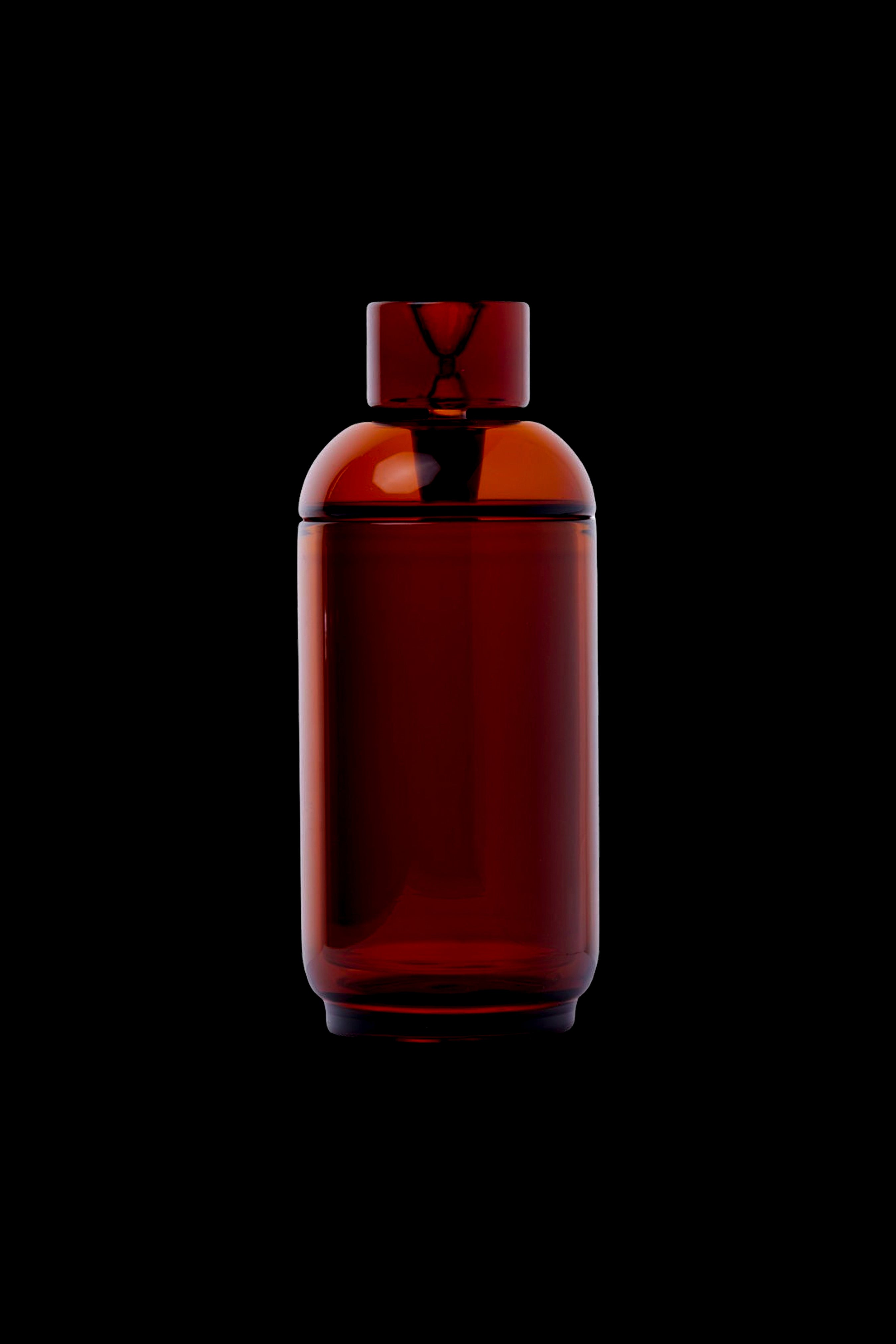 Amber glass cannabis oil vial with a unique hourglass-shaped stopper, isolated on a black background.