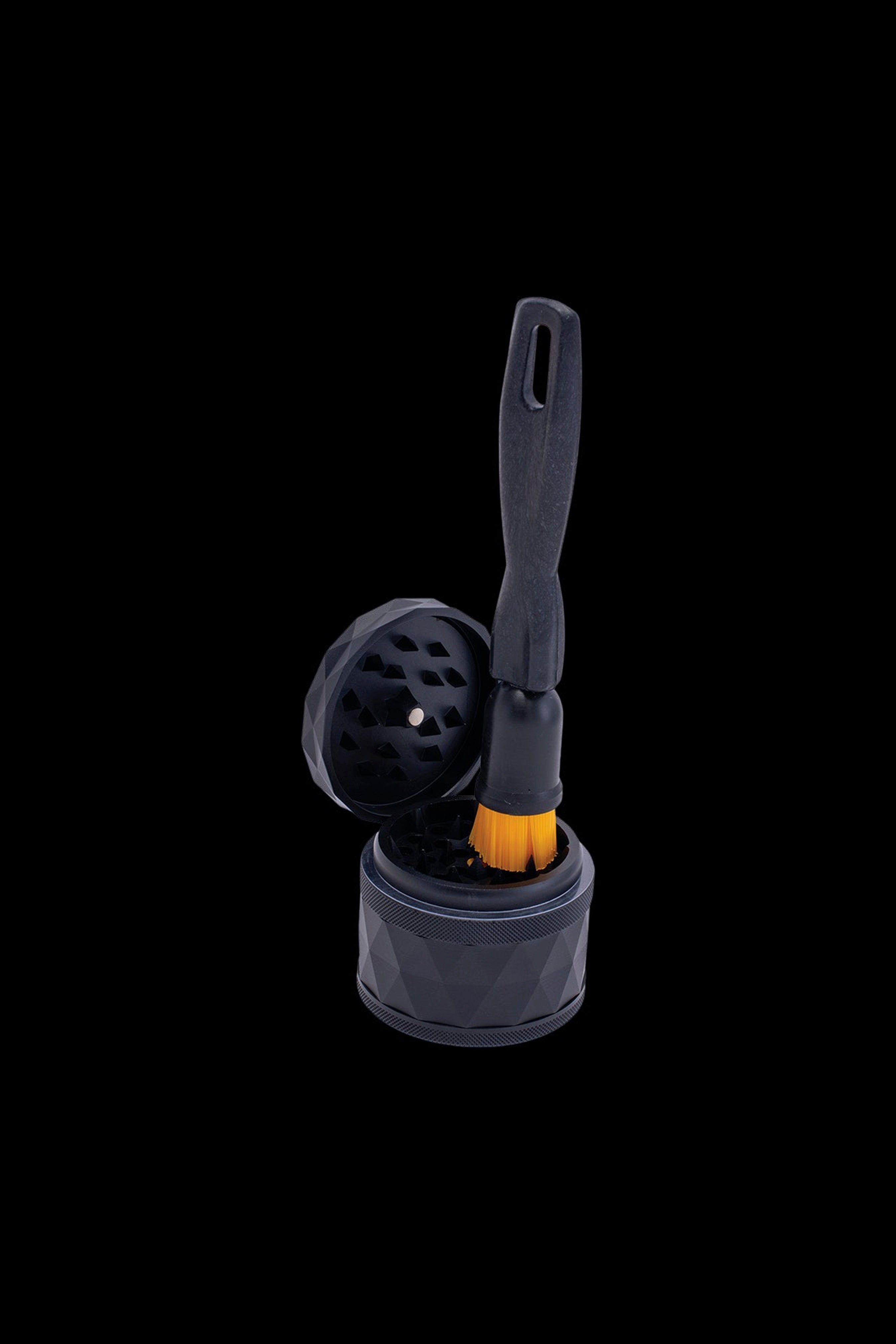 Silver cannabis grinder with open lid and cleaning brush against a black background.