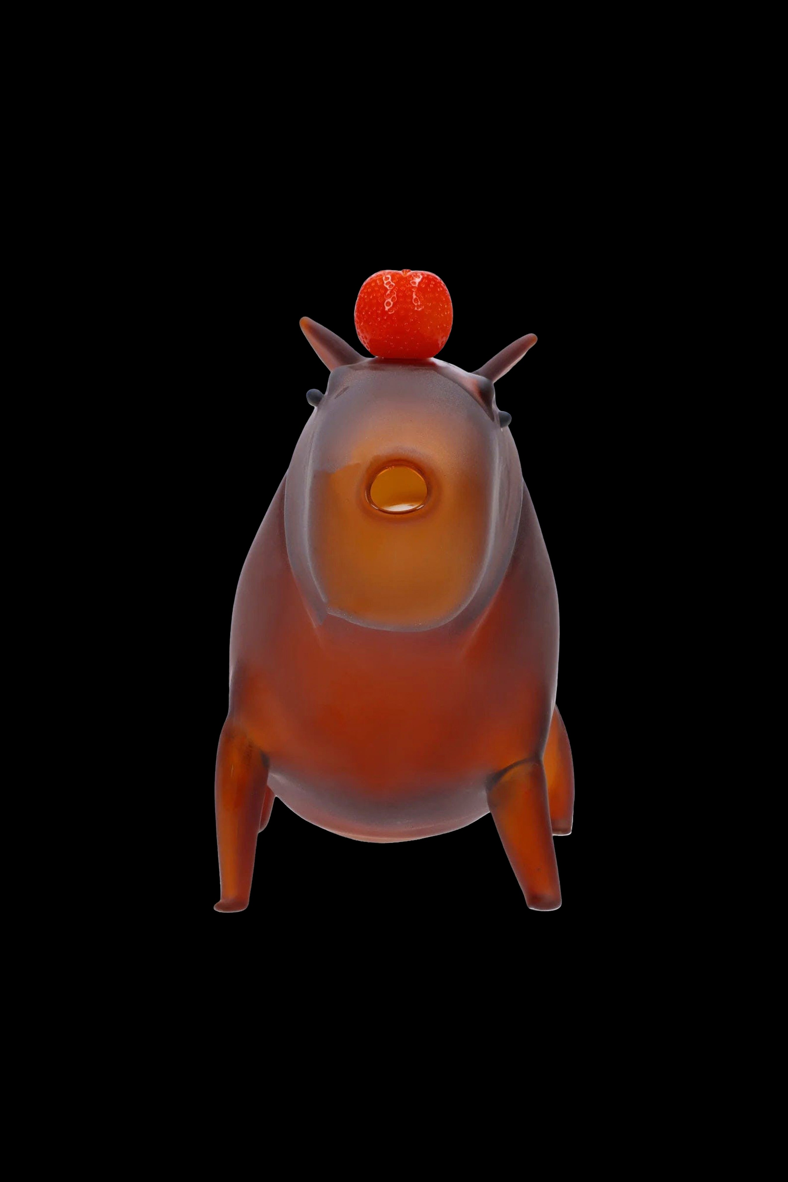 Orange glass water pipe shaped like a pig with a textured orange sphere on top, against a black background.