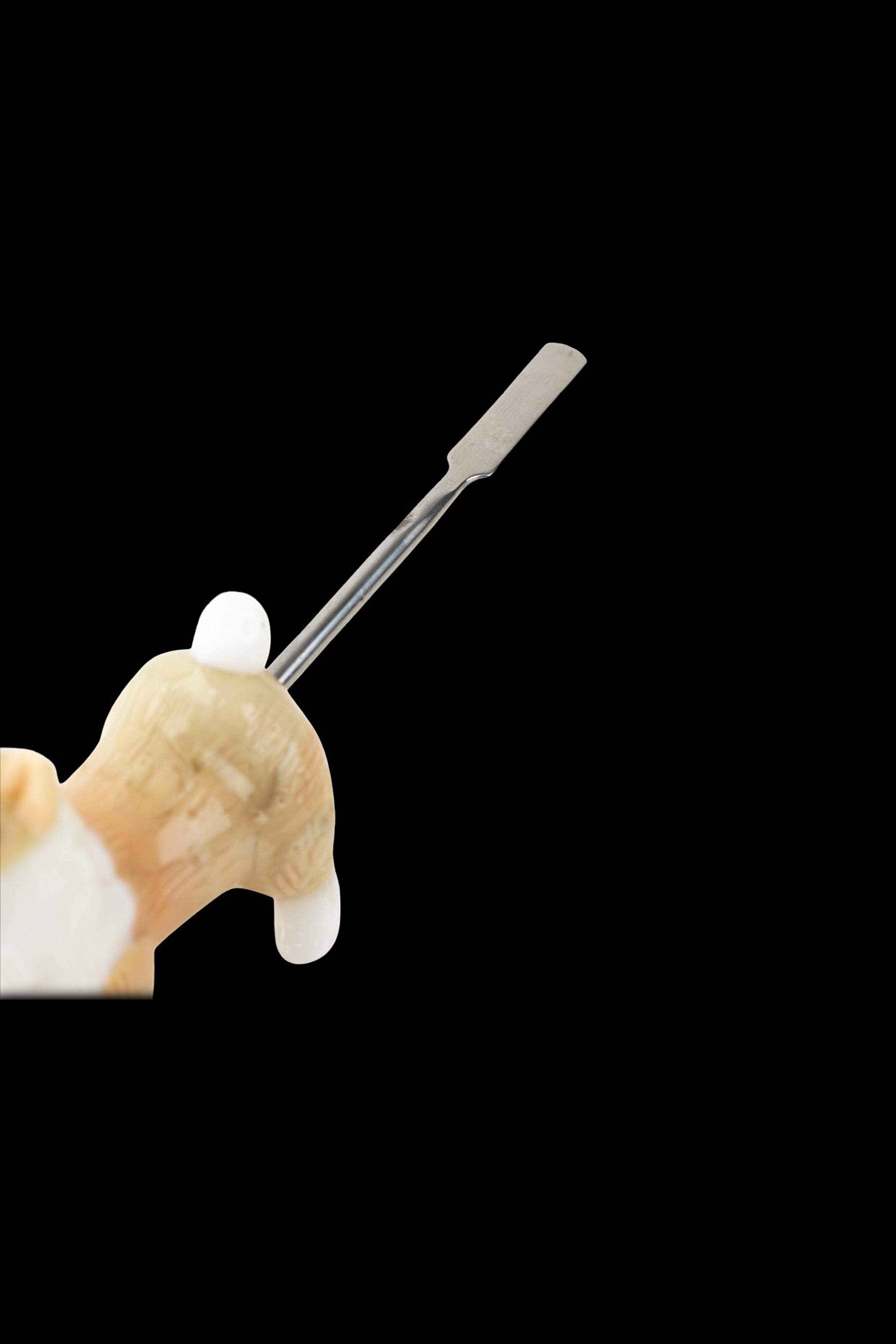 Dab tool held by a plush cat paw against a black background.