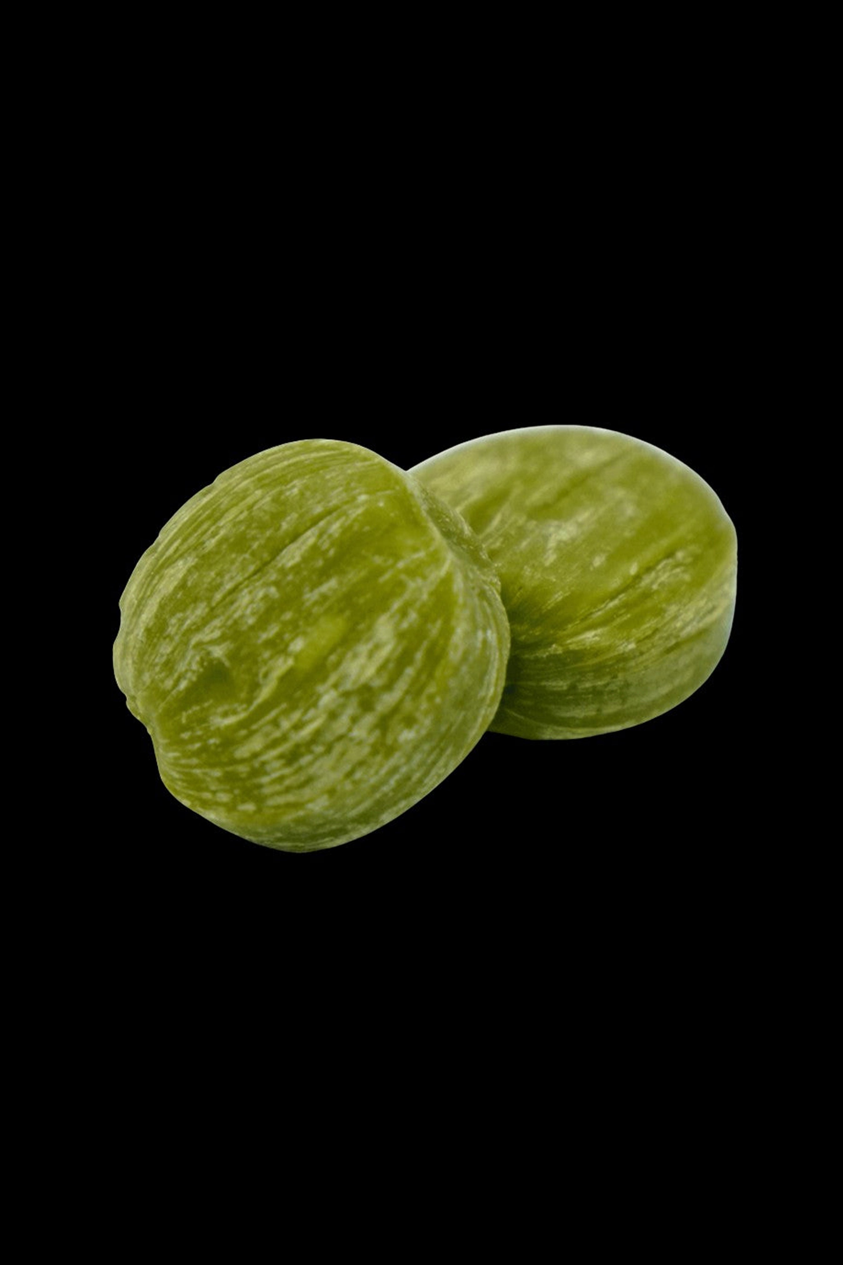 Two green, textured cannabis wax or shatter balls on a black background.