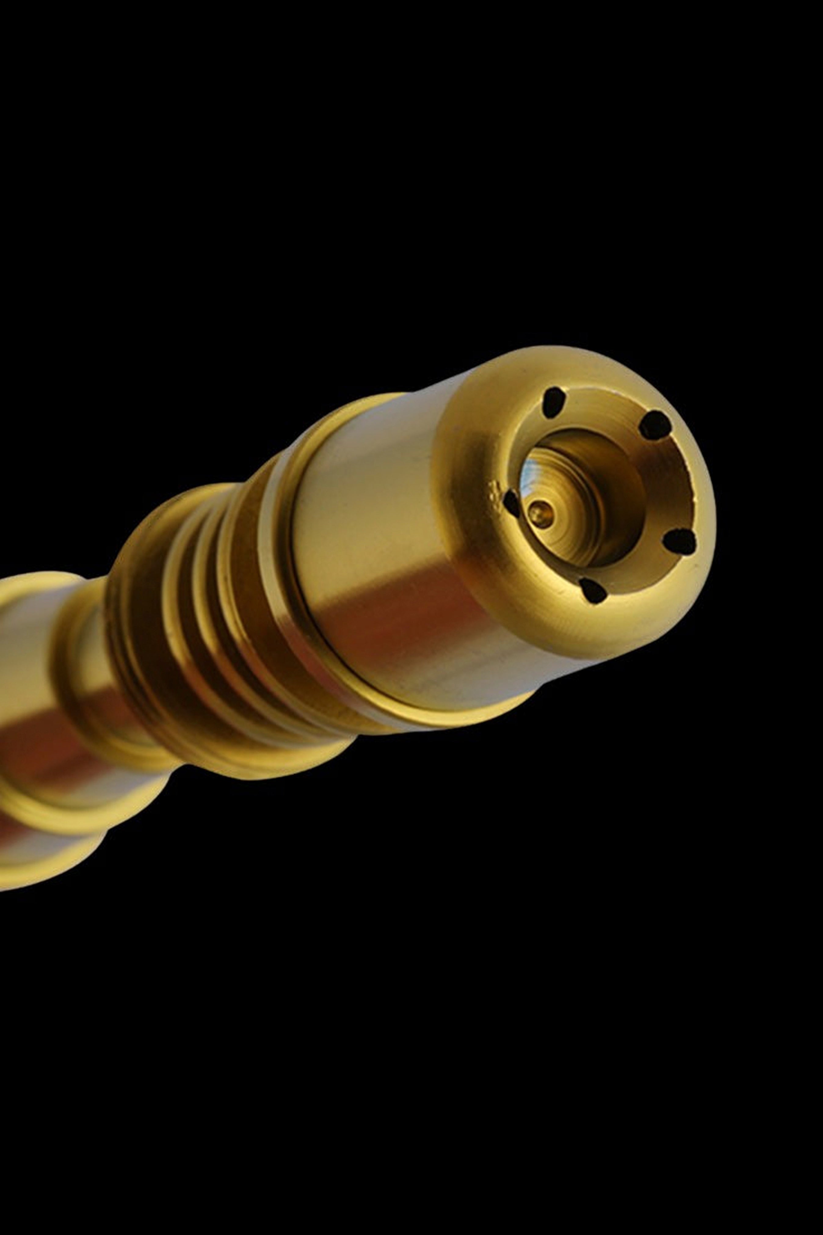 Gold cannabis oil burner tip against a black background.