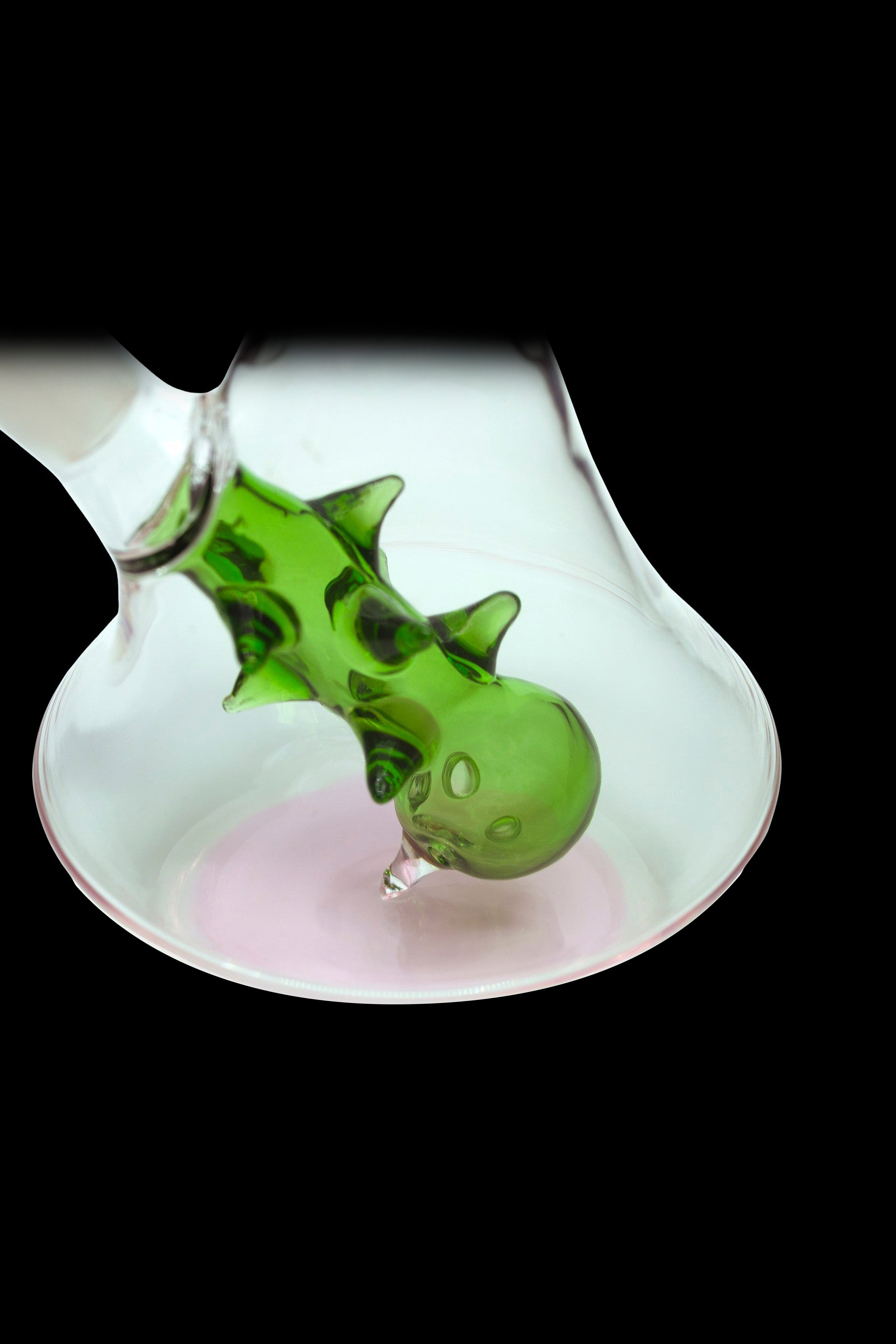 Green glass bubbler with a sculpted dragon design, set against a pink backdrop.