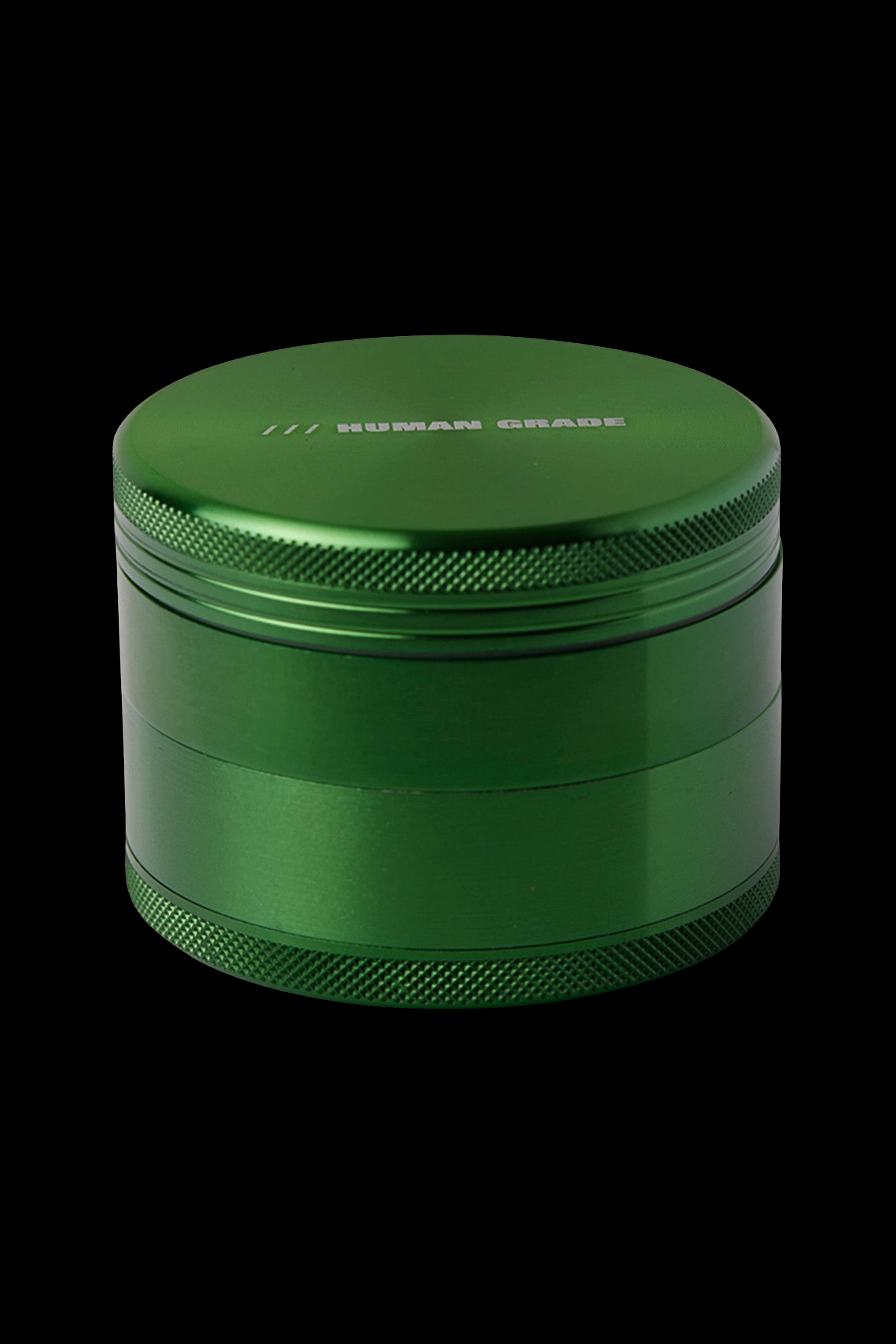 Green four-piece cannabis grinder with "HUMAN GRADE" engraved on the lid.
