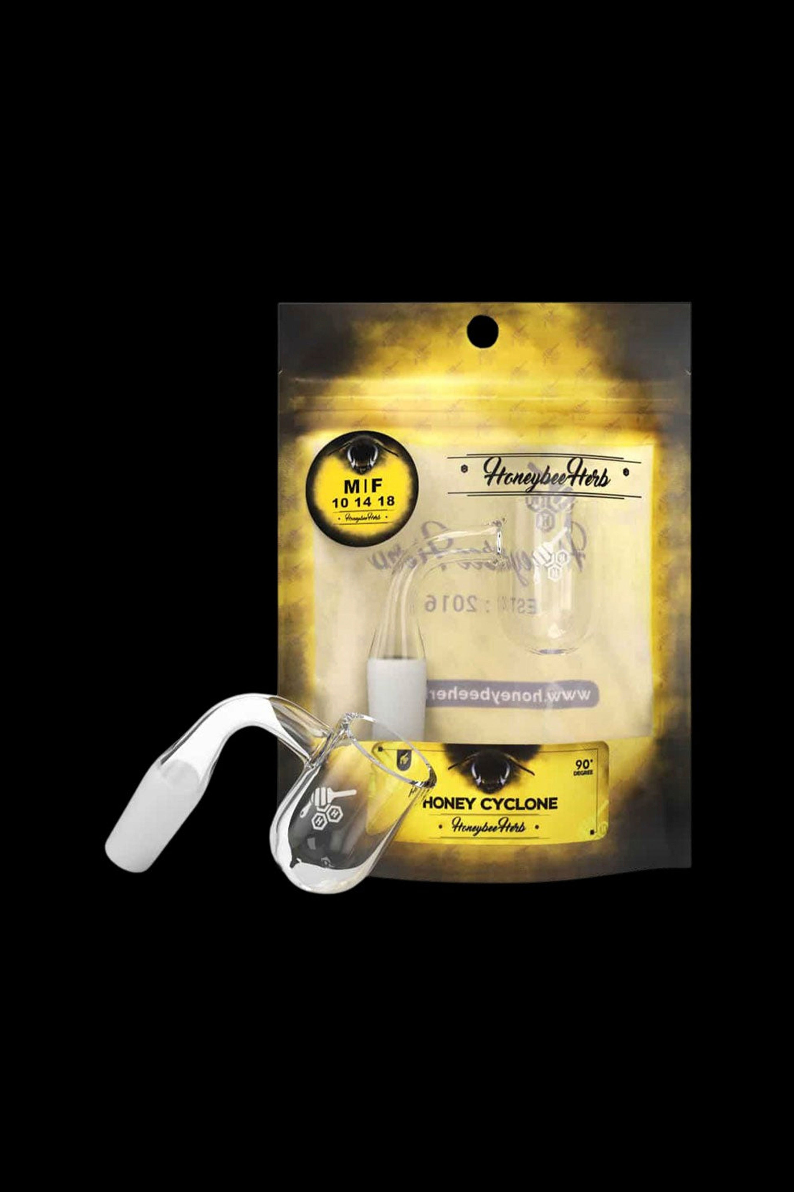 A sealed, gold foil bag of “Honeybee Herb” cannabis, displayed with a clear, spherical cannabis consumption device.