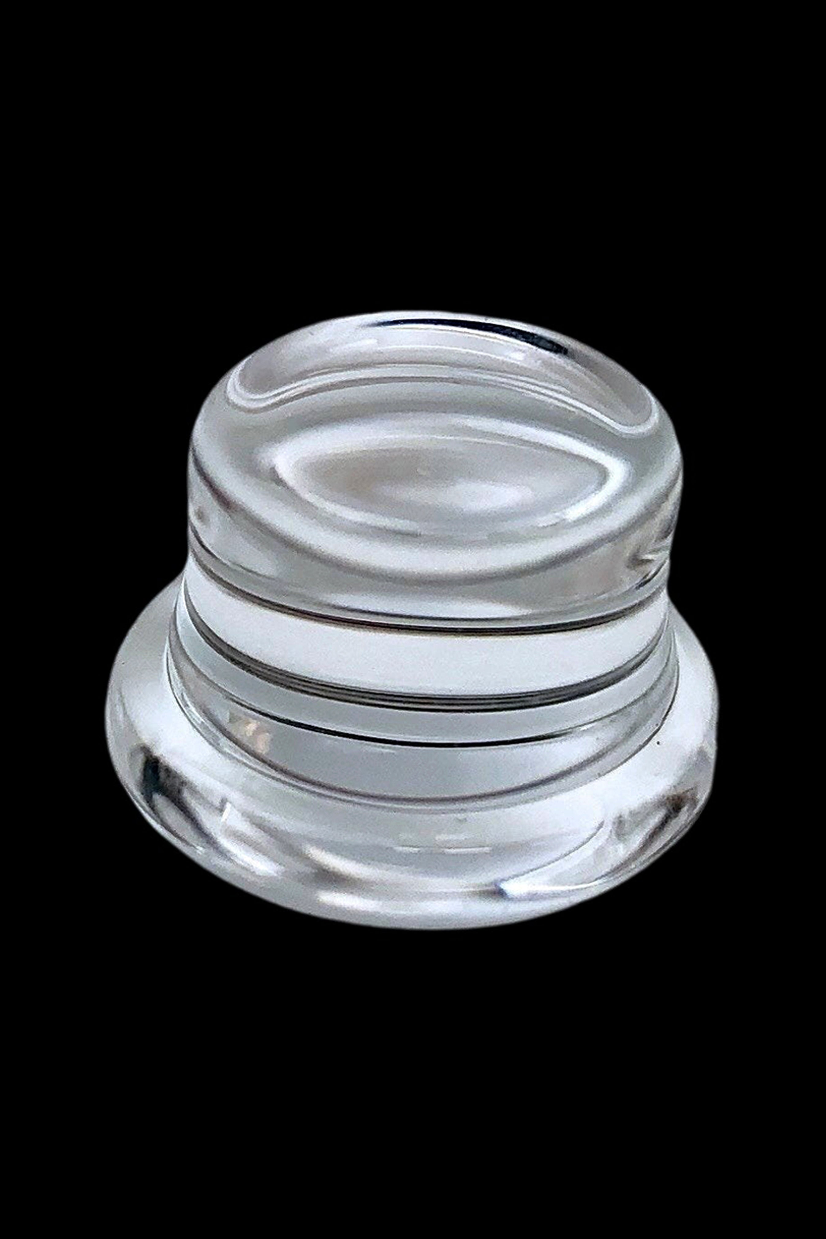 Clear glass dab container against a black background.