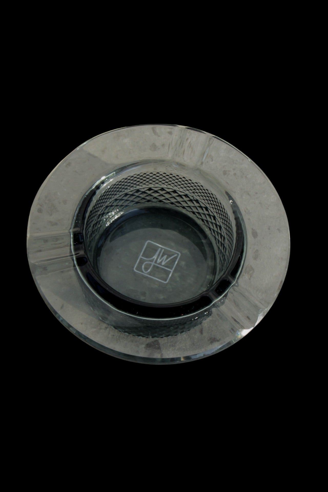 Overhead view of a clear glass ashtray with a patterned base, likely for cannabis use.
