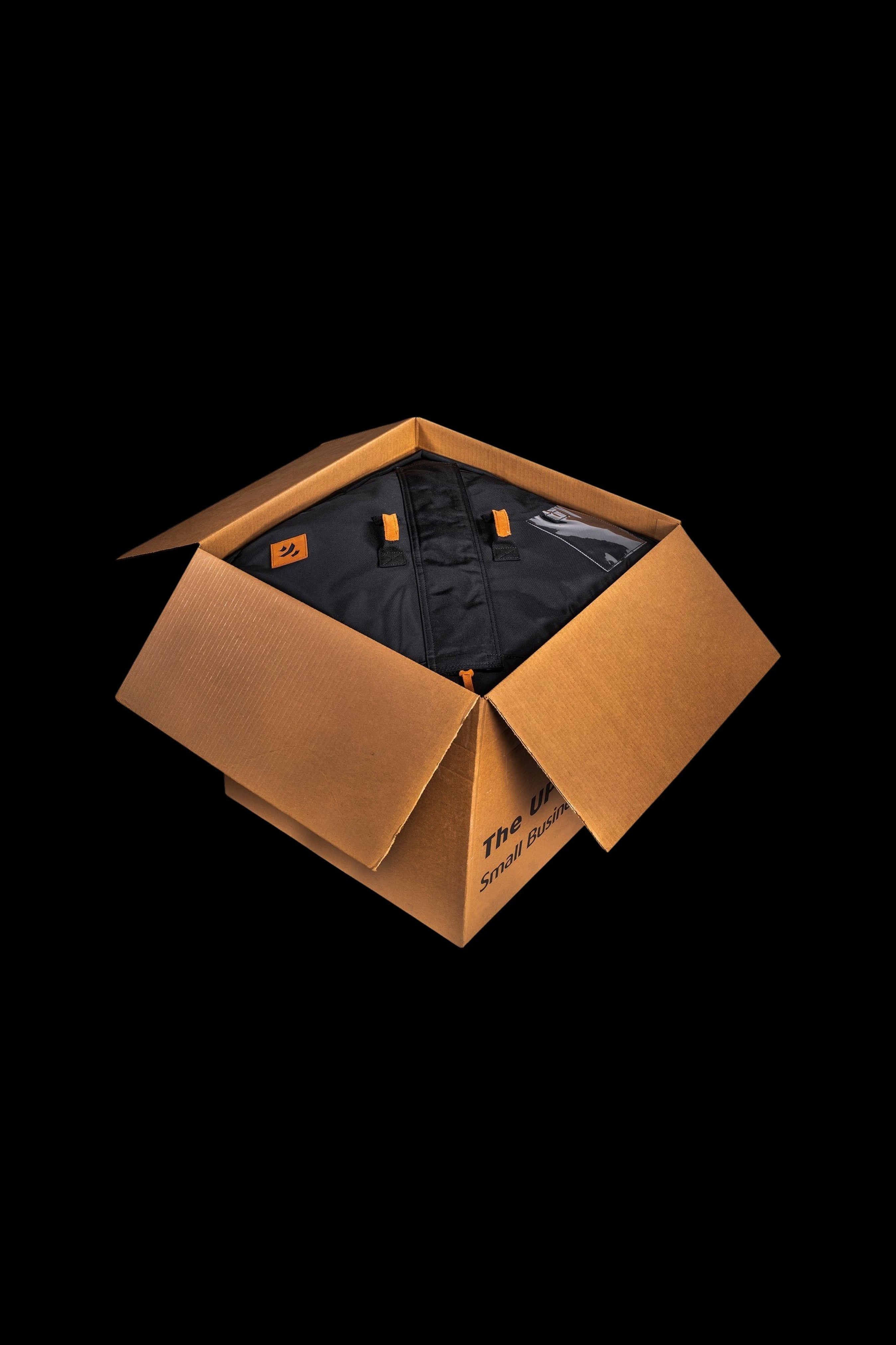 Open cardboard shipping box containing a black smell-proof bag, likely for cannabis or related accessories, with branding visible on the box and bag.