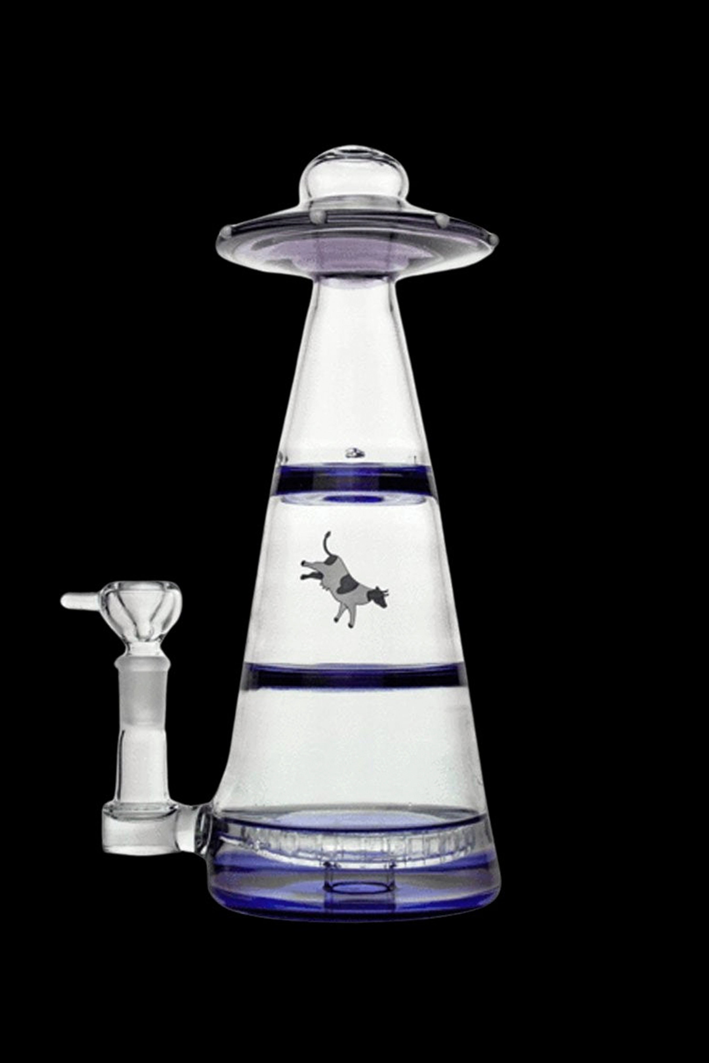 Clear glass water pipe shaped like a UFO with a cowboy riding a bucking bronco silhouetted within the water chamber, against a dark background.