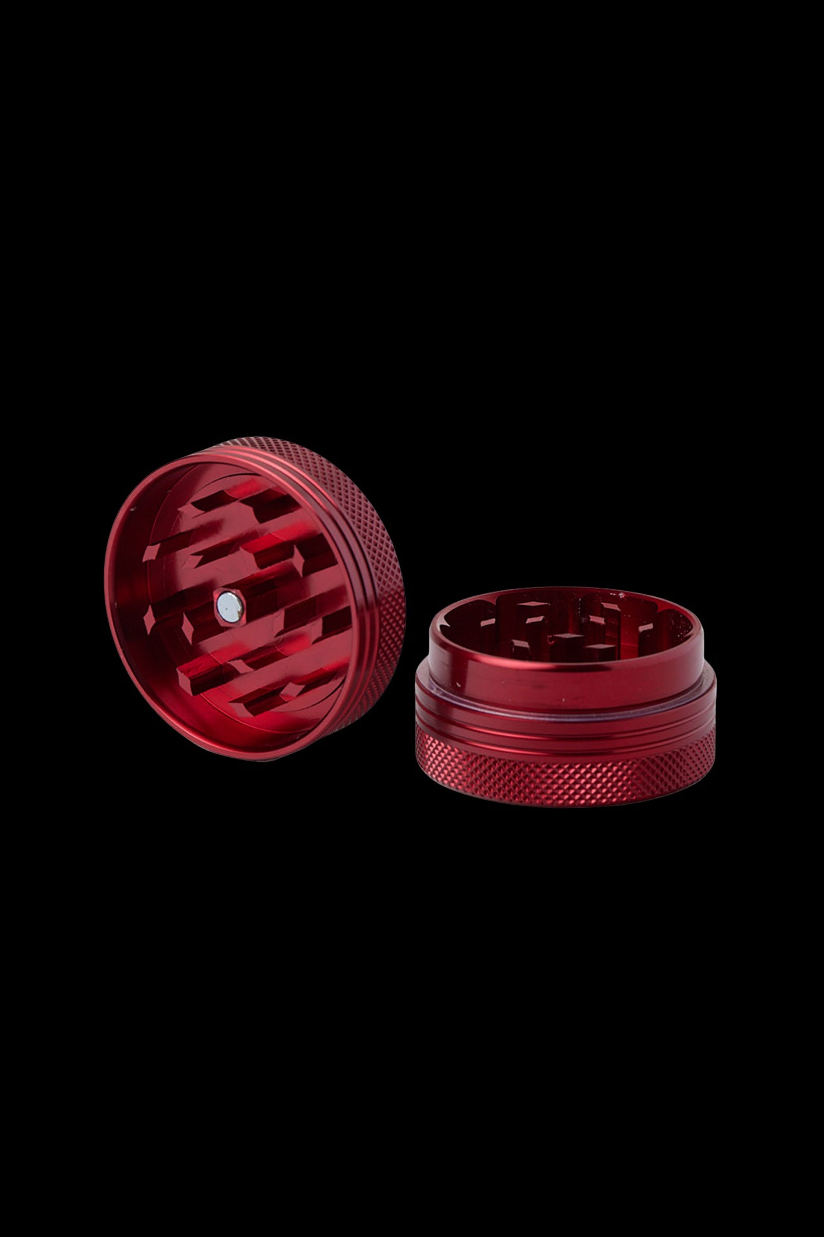 Red four-piece cannabis grinder, disassembled on a black background.