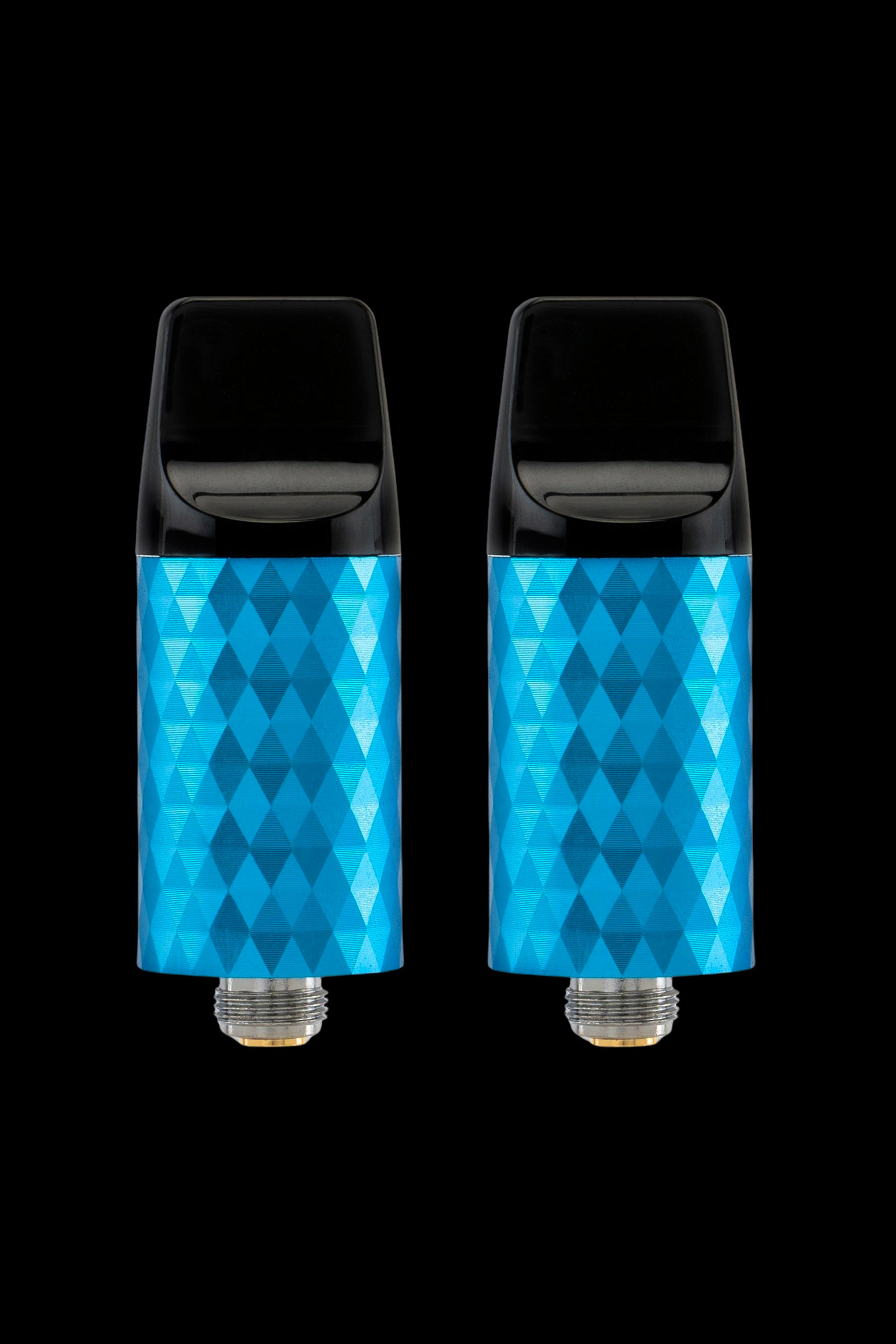 Two blue cannabis oil vape cartridges with geometric patterned bodies against a black background.