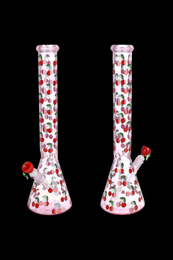 Two pink glass bongs decorated with a red cherry pattern against a black background.