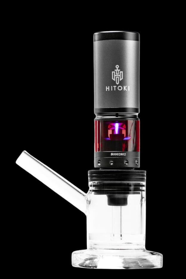 White glass rig with a black electronic dab nail (E-nail) displaying a red light, branded with “HITOKI.”