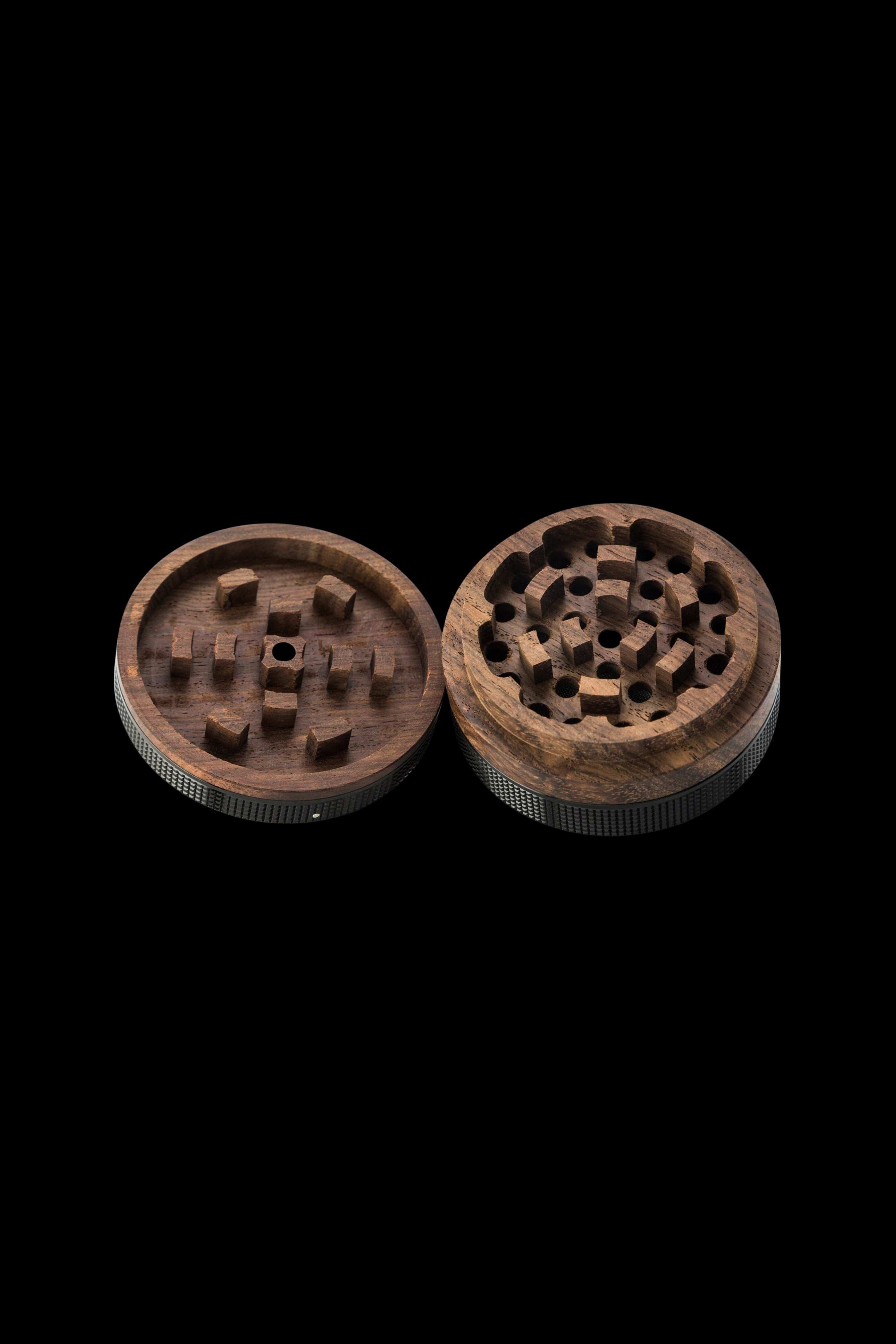 Wooden cannabis grinder, disassembled, on a black background.
