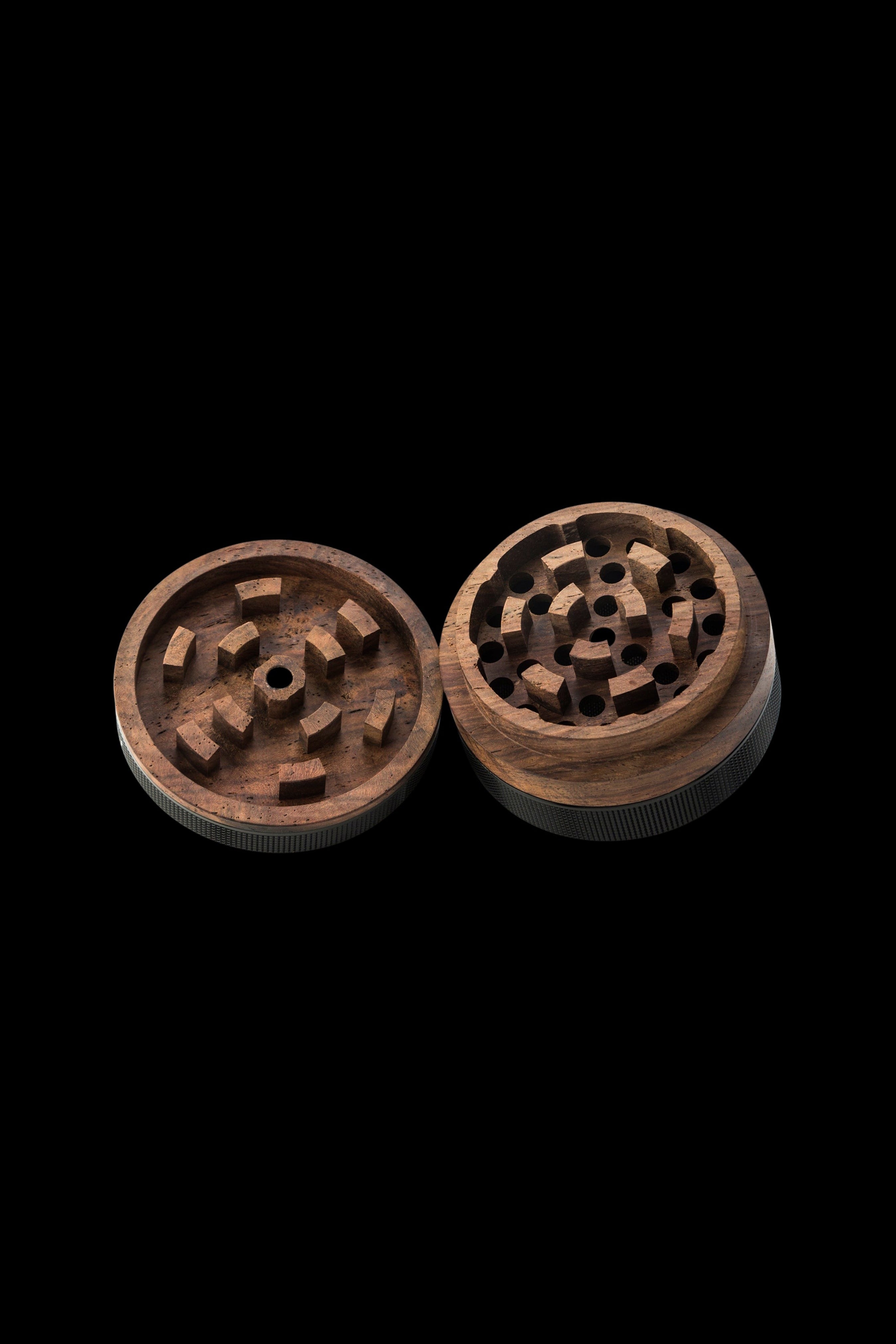 Wooden cannabis grinder, disassembled, on a black background.