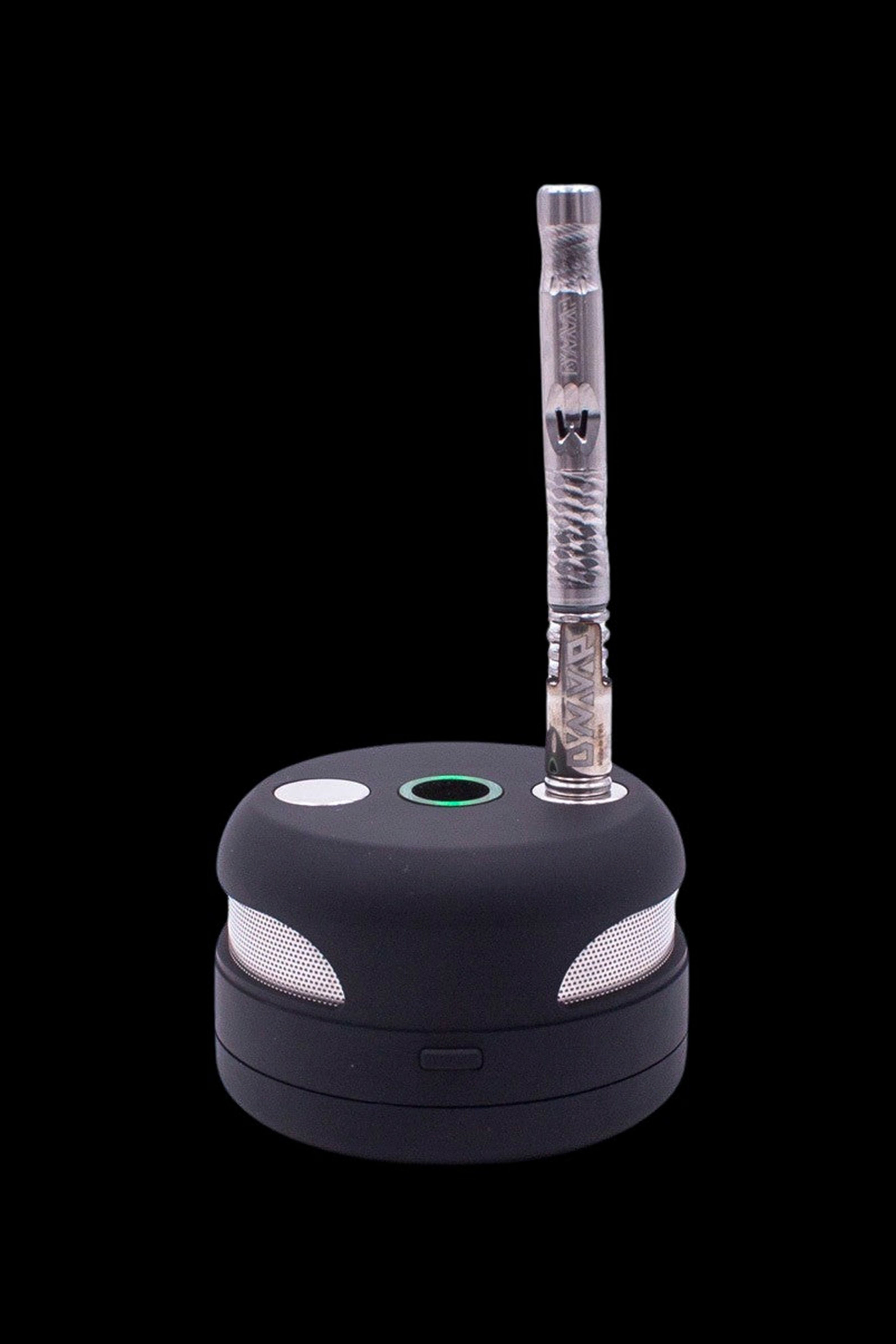 Black cannabis vaporizer pen docked on its charging base.