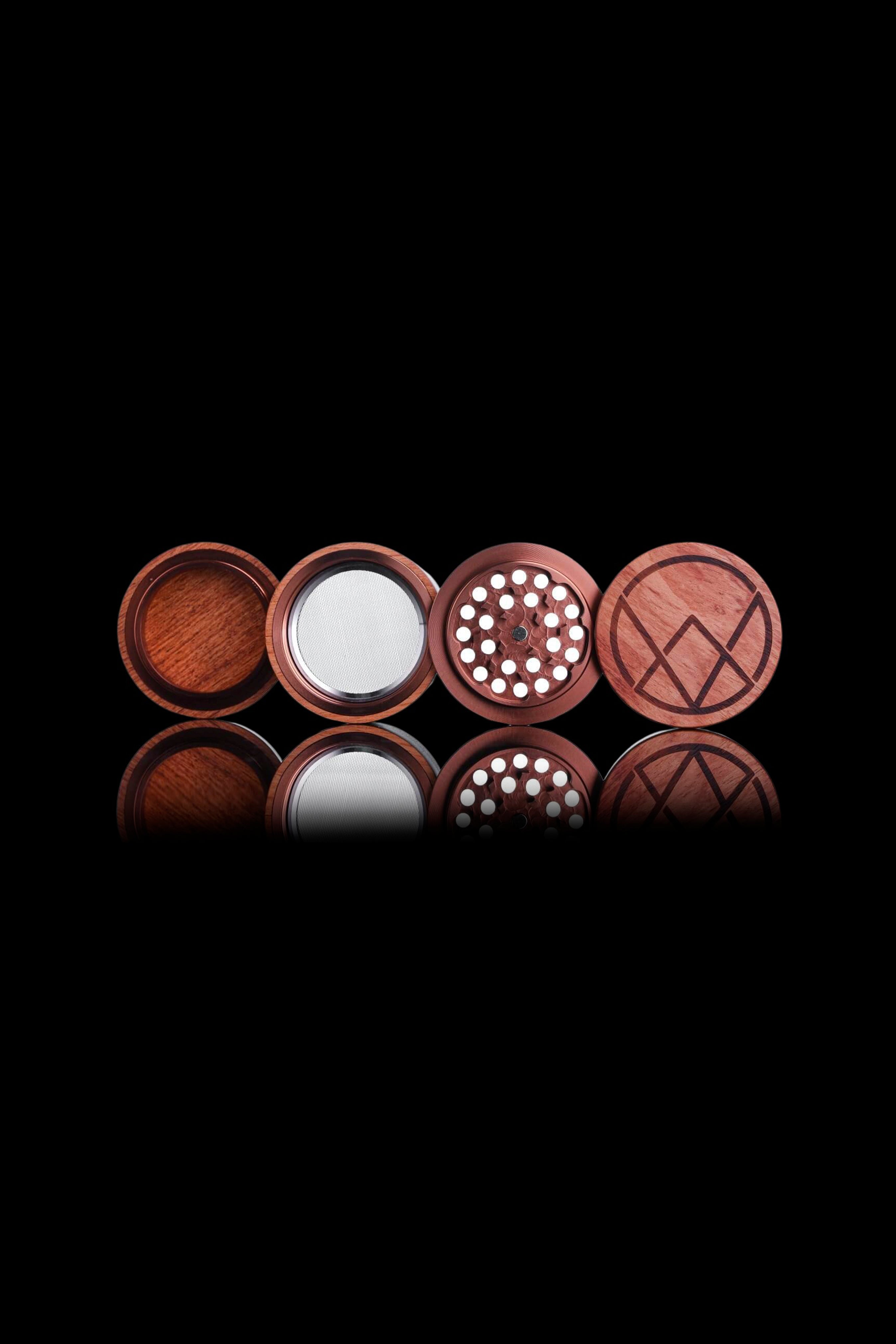 Wooden cannabis grinder components displayed on a reflective surface against a black background.