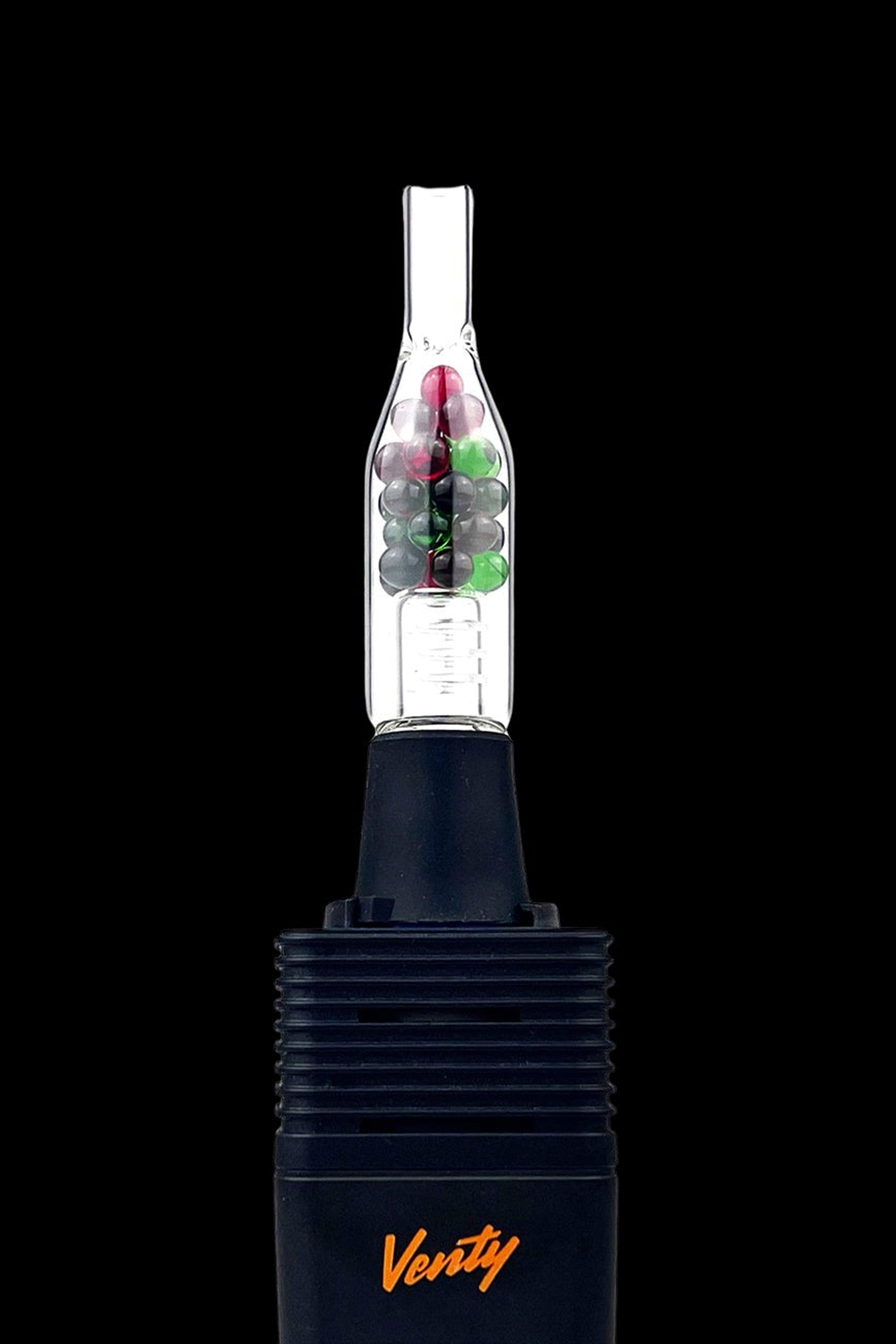 Black cannabis vaporizer with a glass bubbler attachment filled with green and purple cannabis buds. "Verity" is branded on the device.