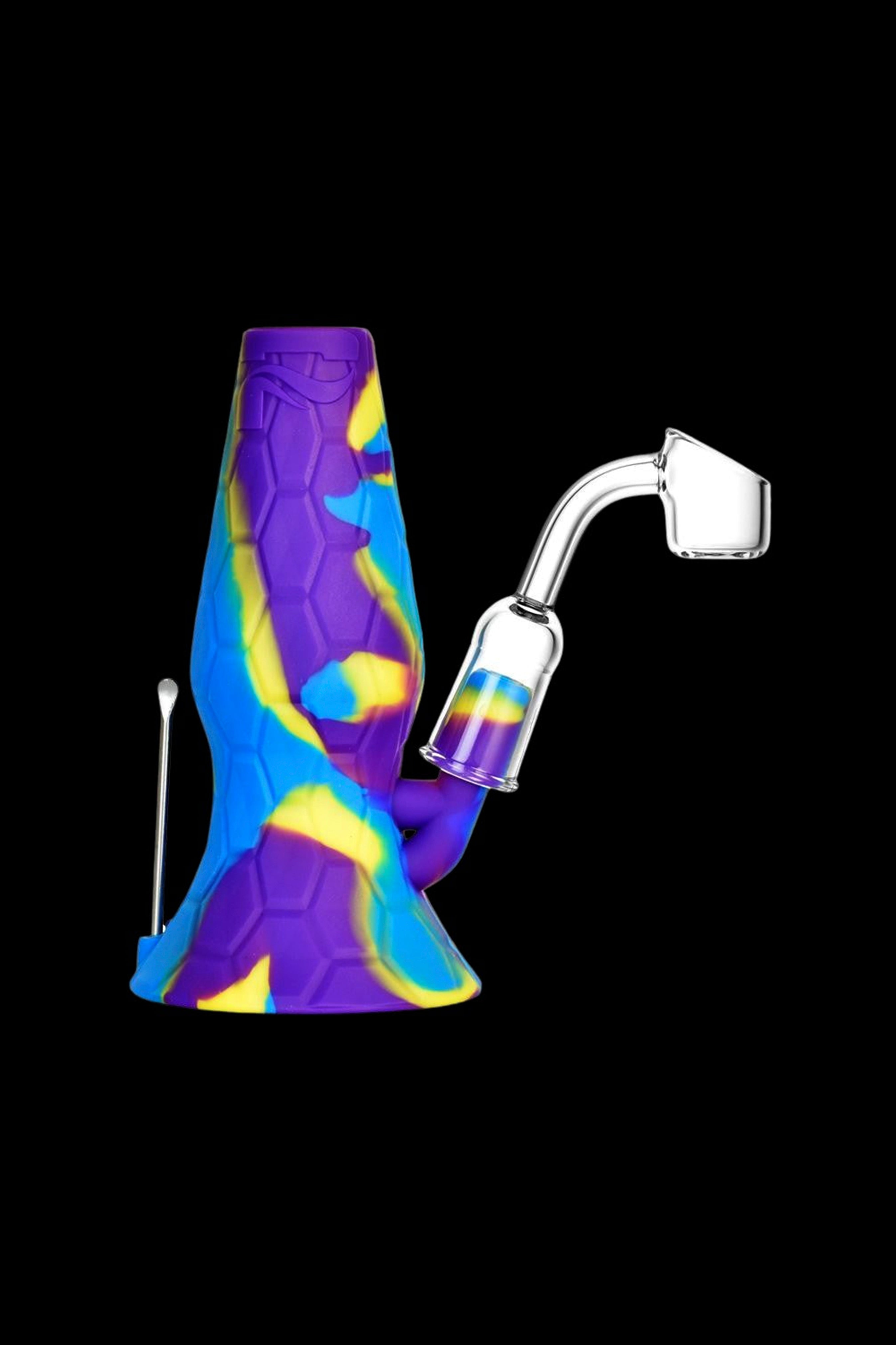 Silicone dab rig with quartz banger and tool against a black background.