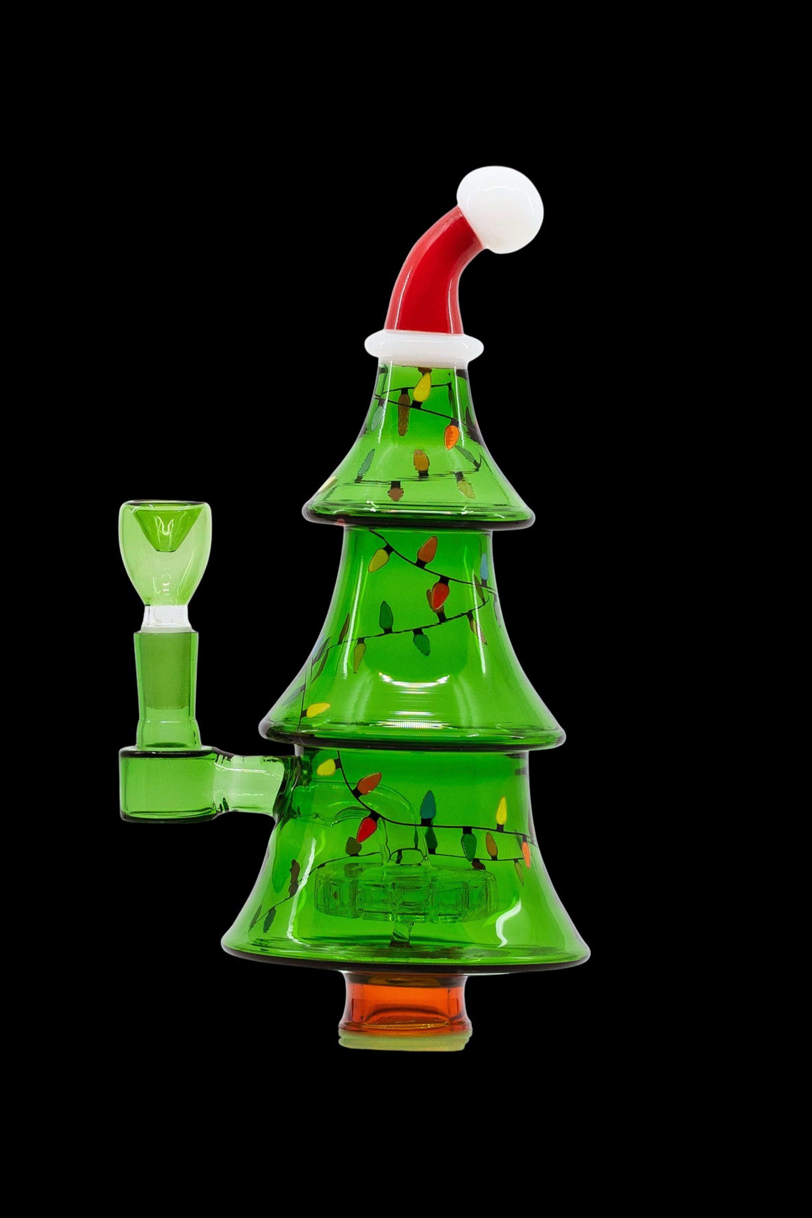 A glass cannabis water pipe shaped like a Christmas tree, adorned with colorful lights and a Santa hat.