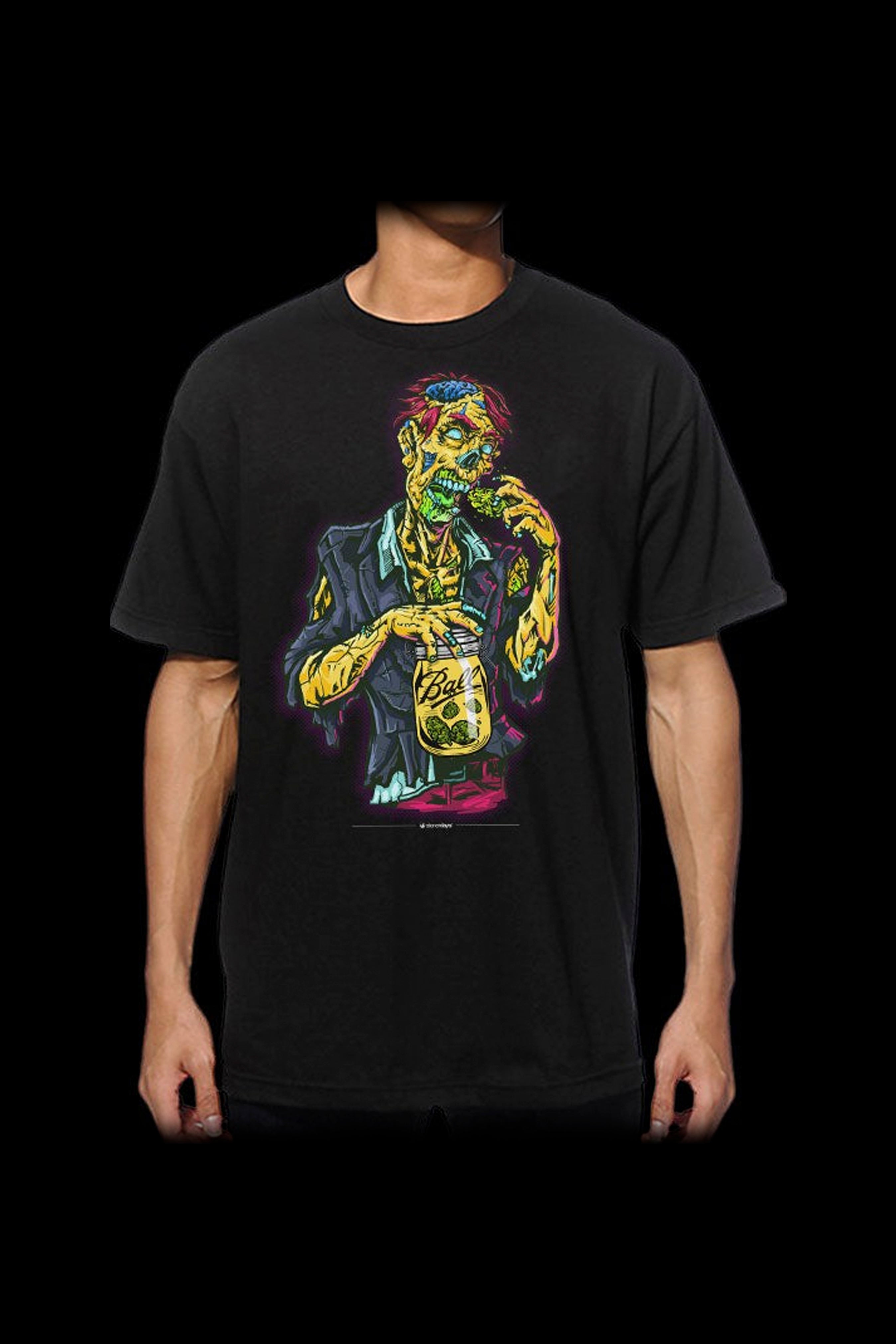 A person wearing a black t-shirt with a colorful graphic of a zombie thoughtfully holding a jar of cannabis.