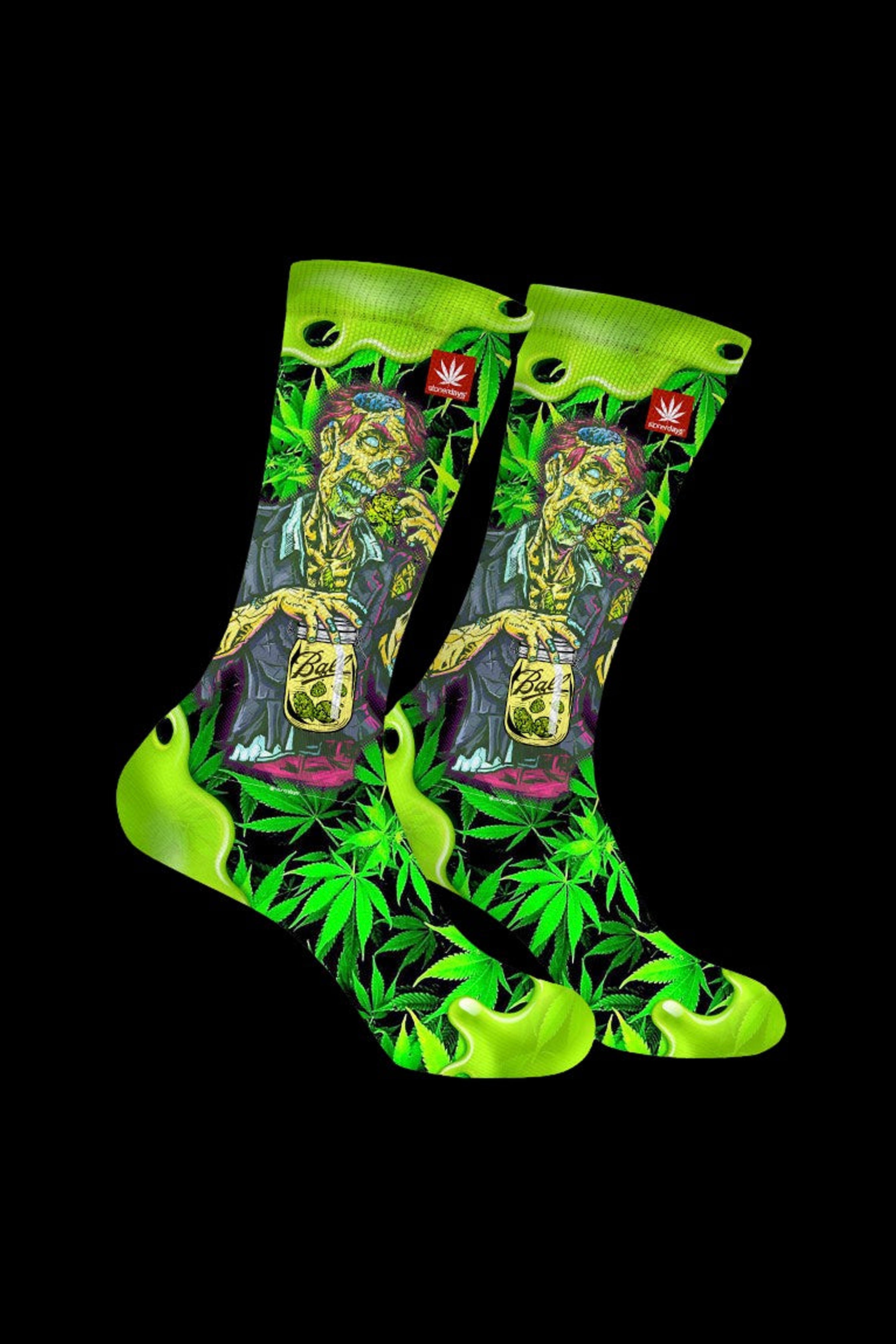 Green cannabis-themed crew socks with a mason jar design and marijuana leaf patterns, displayed against a black background.
