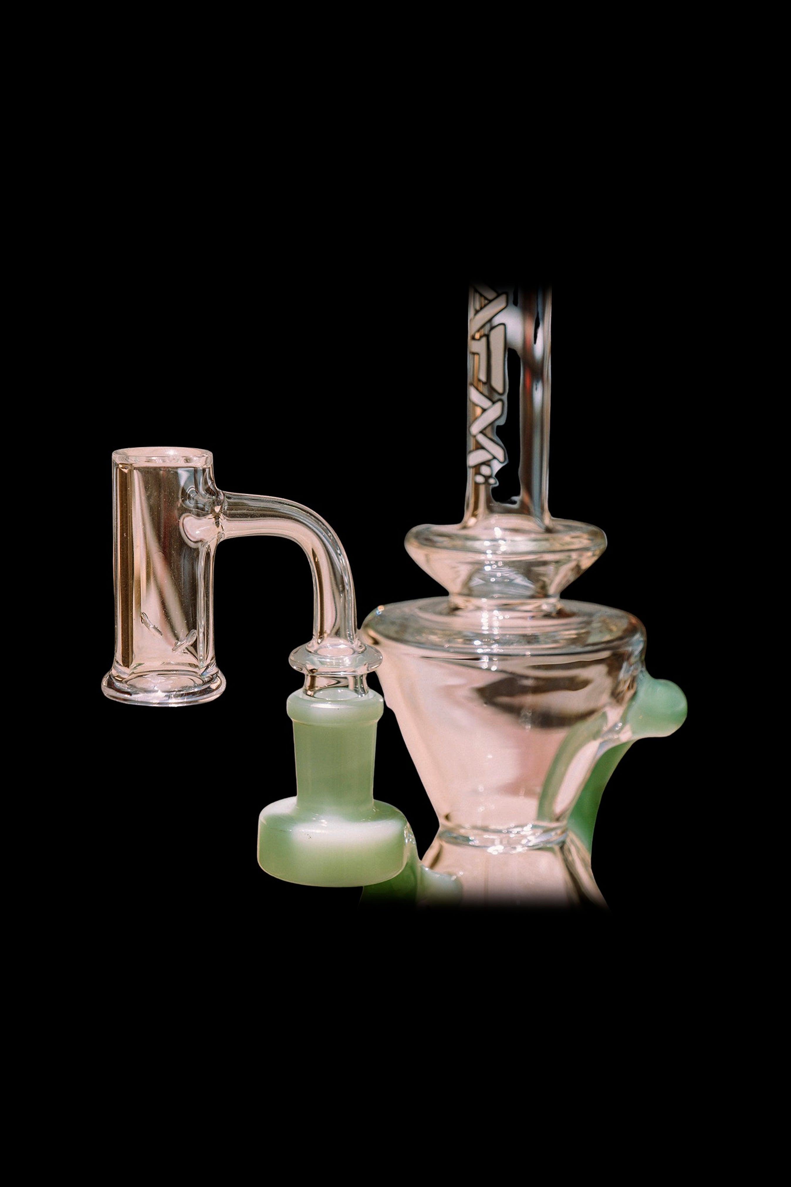 Hand-blown glass rig with quartz banger, featuring a swirling pink and green color scheme.