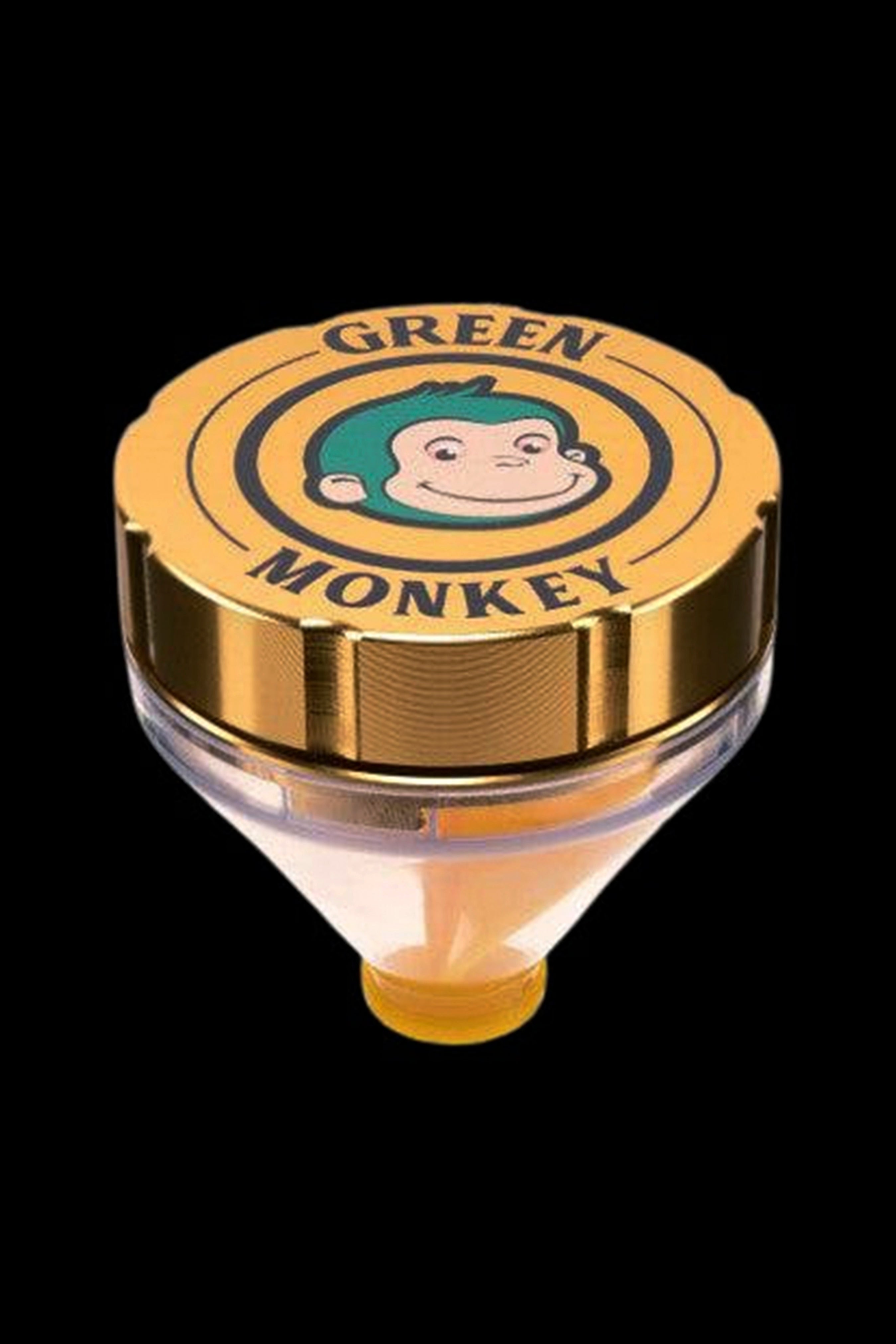 Close-up top-down view of the Green Monkey Patas Grinder showing its gold lid with a smiling green-haired monkey logo against a black background.