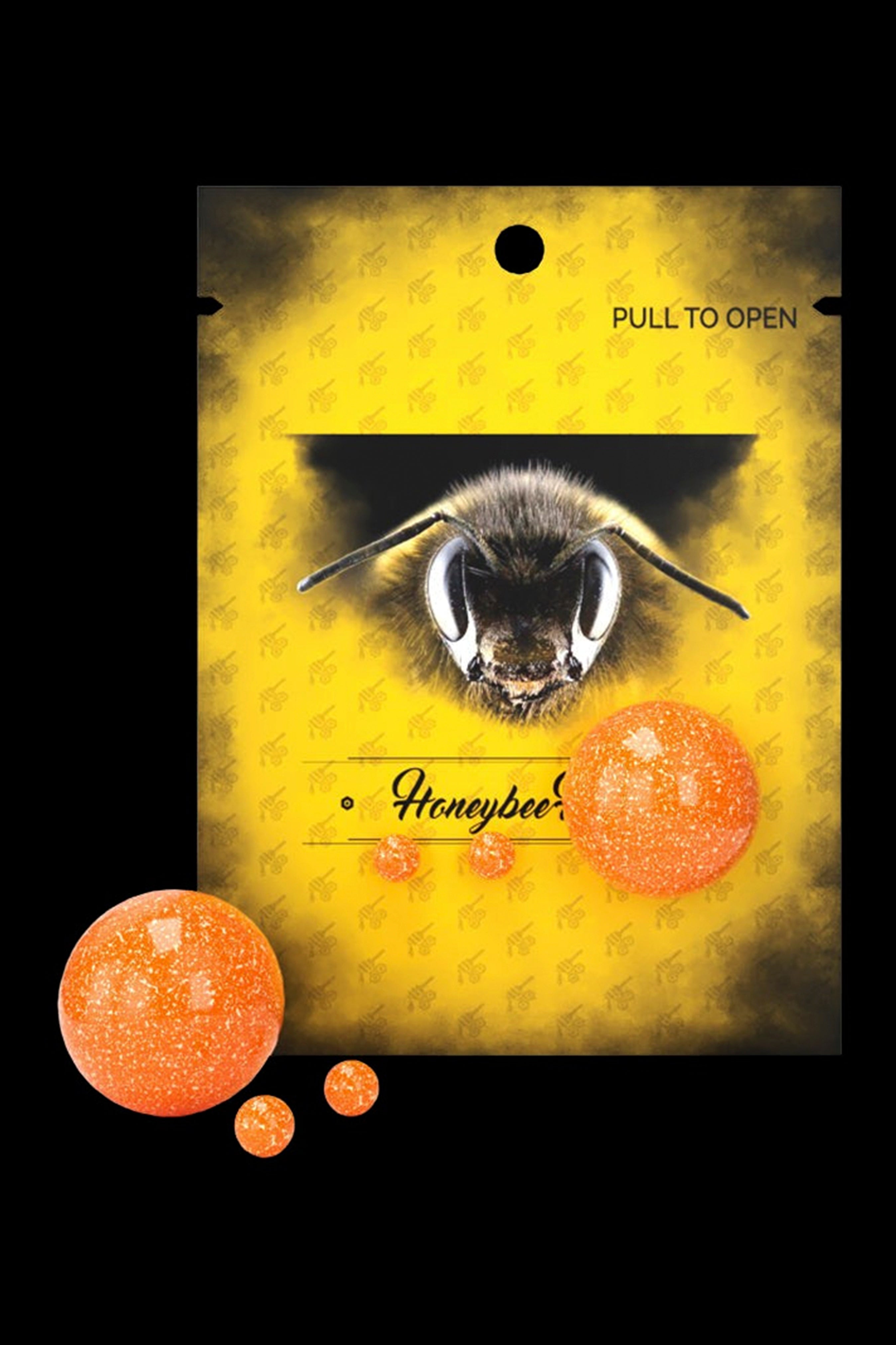 Yellow cannabis edible bag labeled “Honeybee” with a bee illustration and scattered orange cannabis candies.