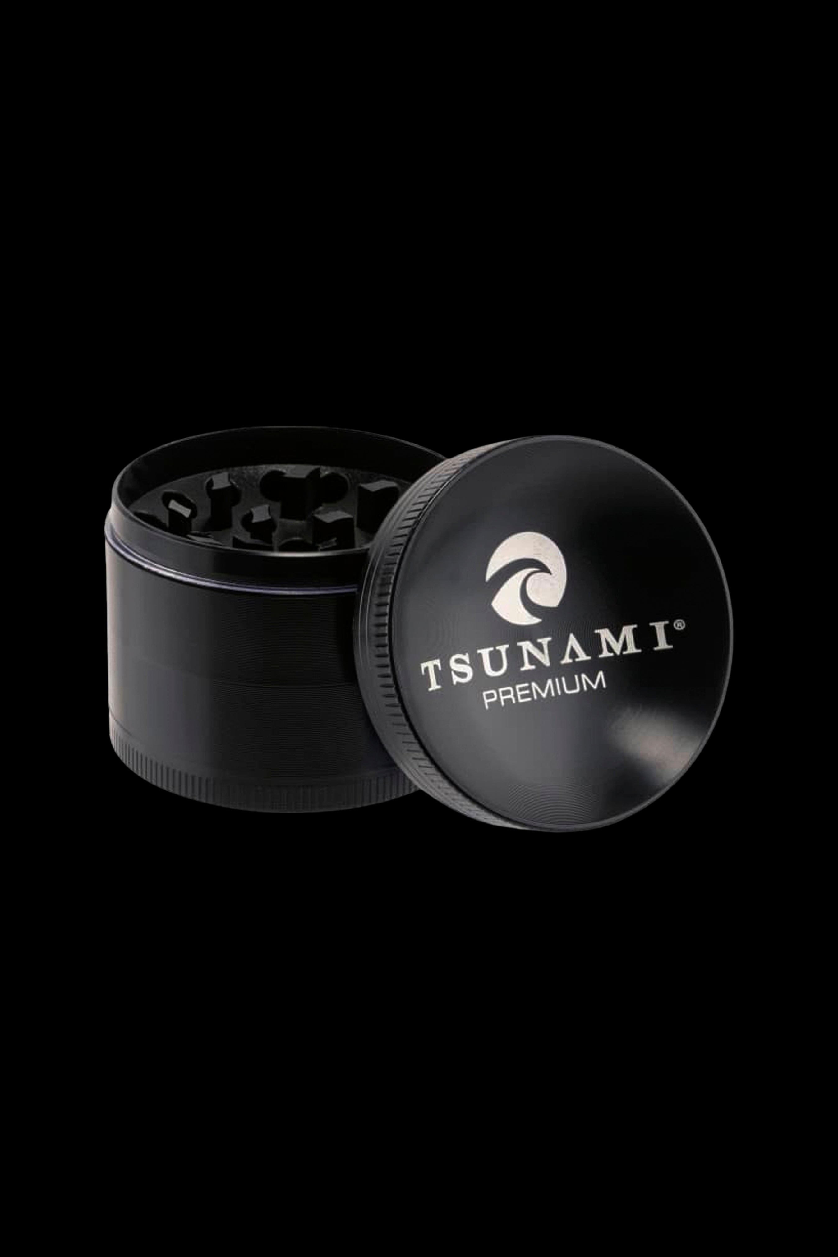 Black metal cannabis grinder with open lid displaying “Tsunami Premium” logo.