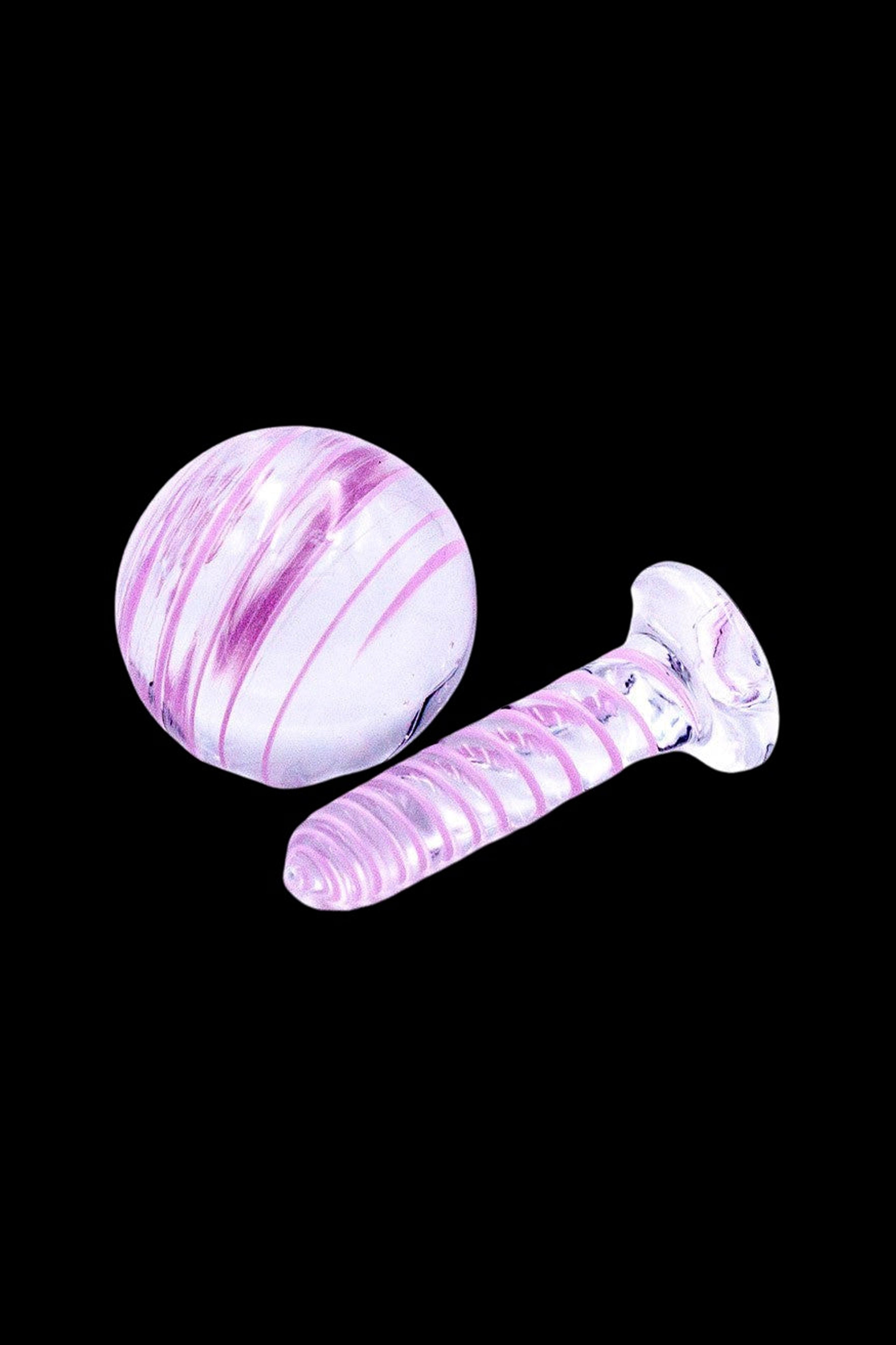 Iridescent pink glass cannabis water pipe and mouthpiece on a black background.