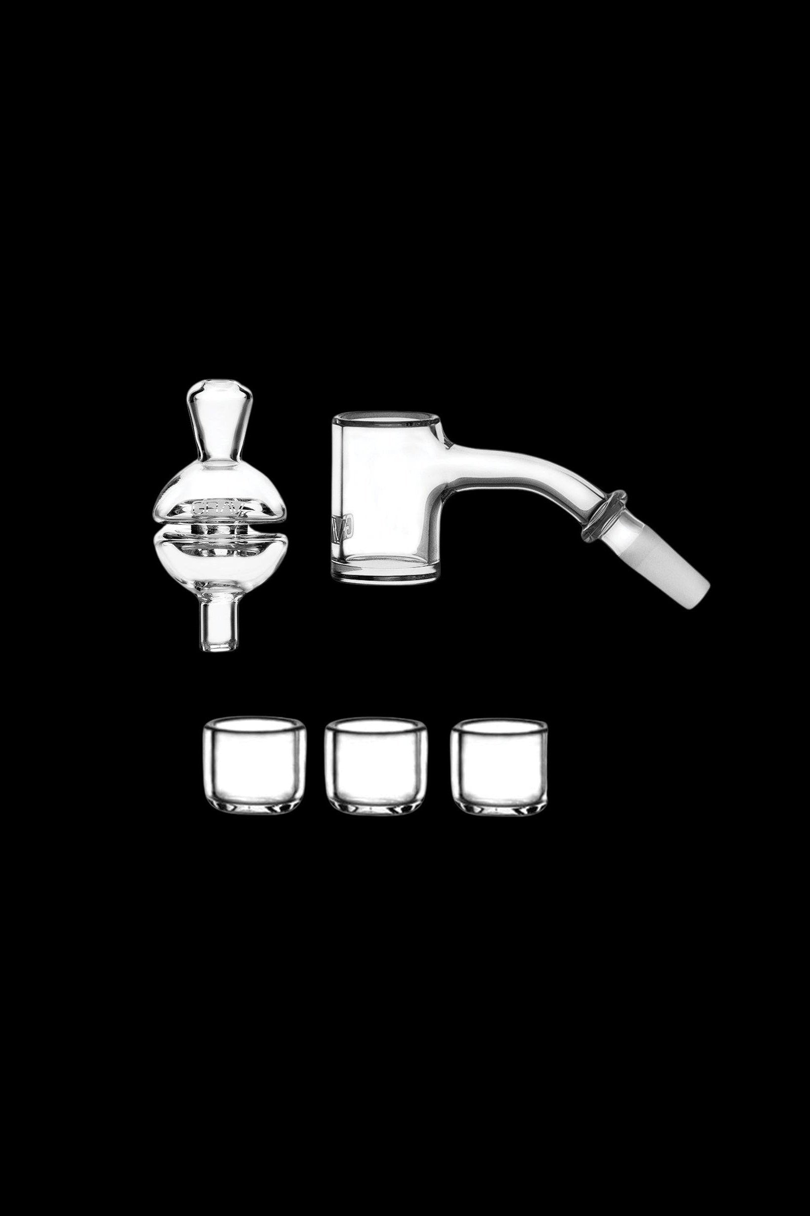 Clear glass dab rig components including a quartz banger, carb cap, and four small glass storage containers, isolated on a black background.