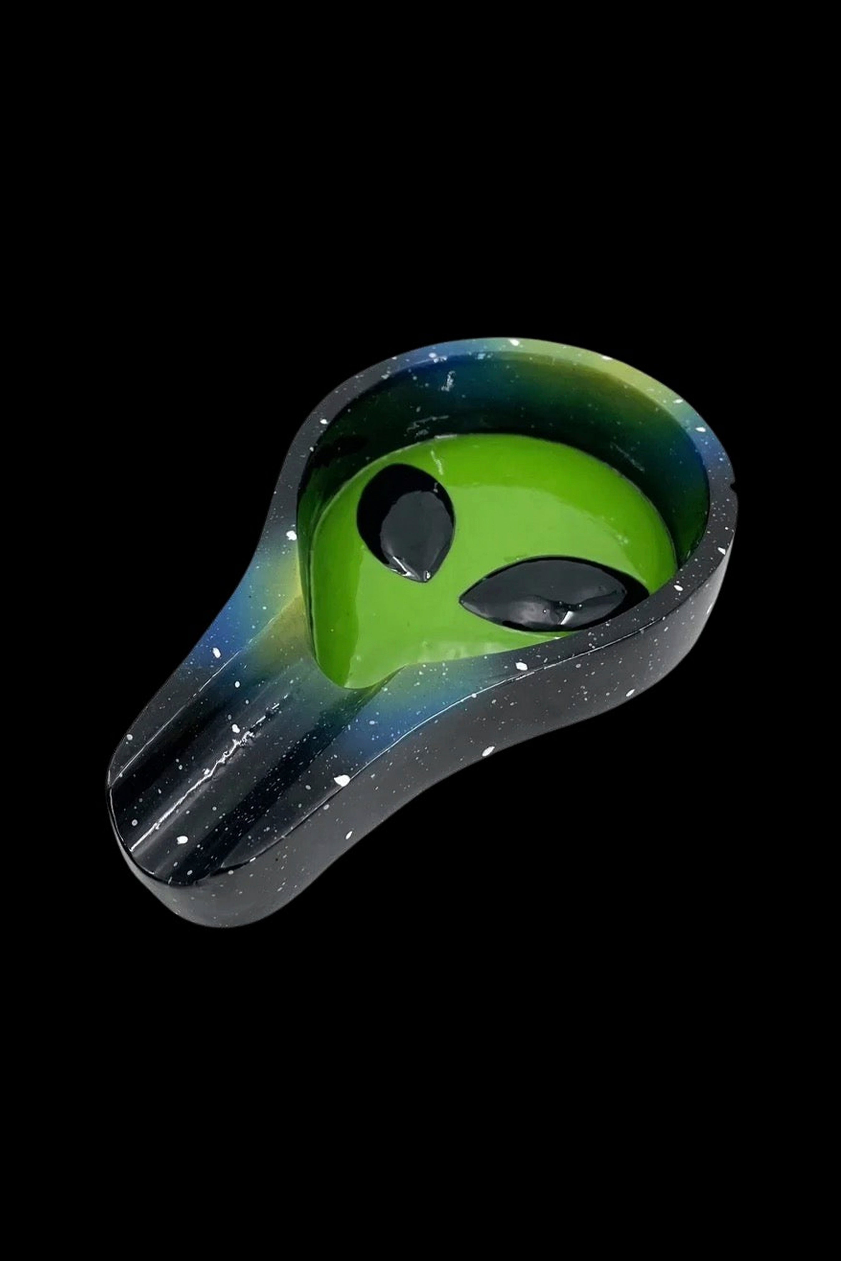 Alien-shaped ashtray with a speckled galaxy design, isolated on a black background.